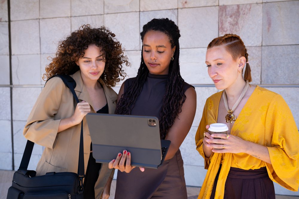 Three African American and white women collaborating outdoors