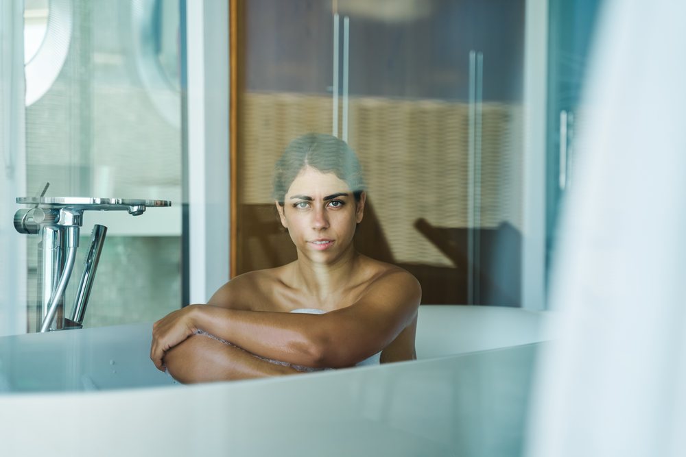 A white woman relaxing in a bathtub in a modern bathroom