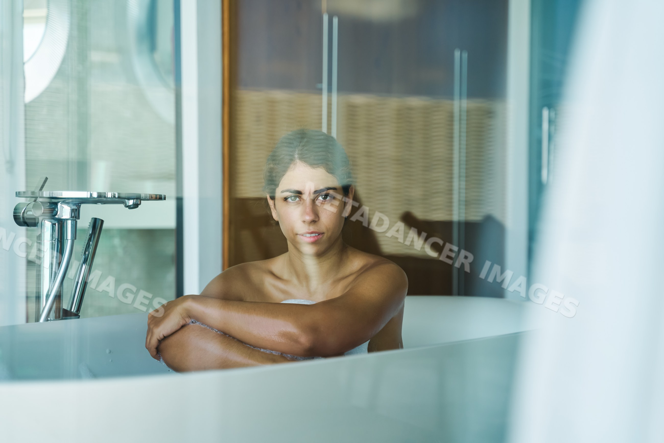 A white woman relaxing in a bathtub in a modern bathroom