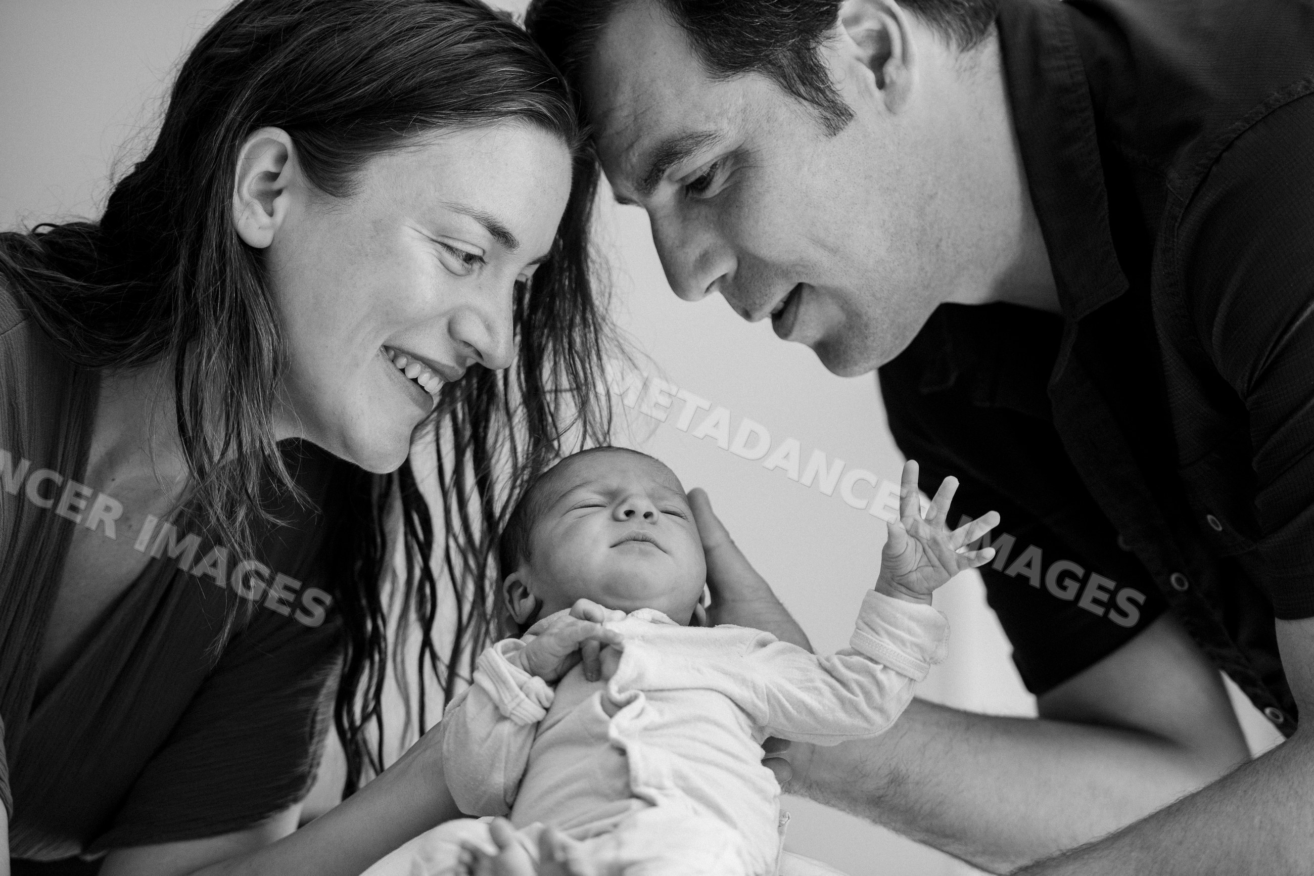 Newborn baby with parents in tender moment indoors