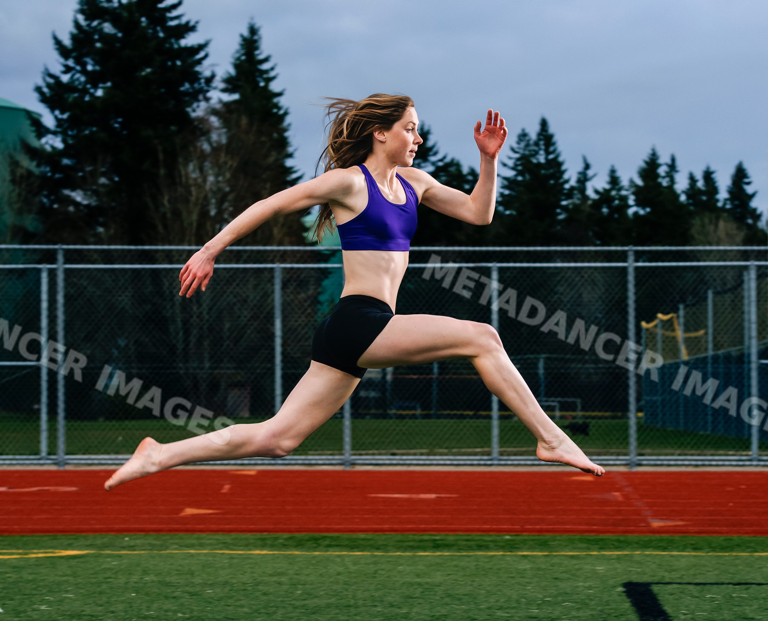 White woman athlete jumping on outdoor track field