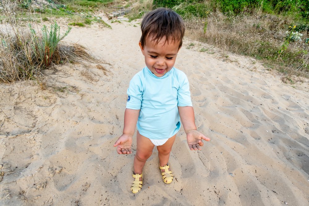 Toddler playing with sand at the beach in Spain