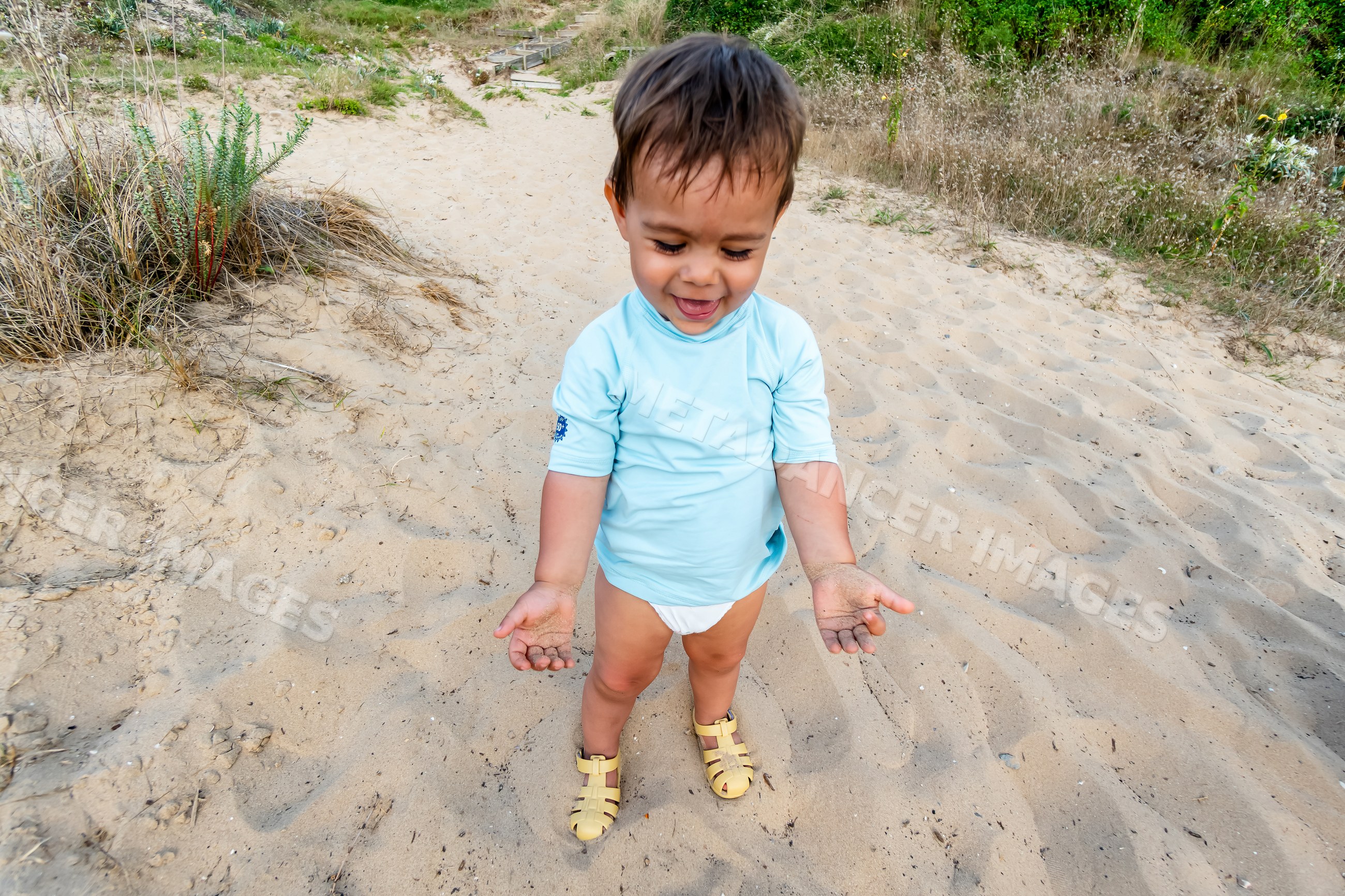 Toddler playing with sand at the beach in Spain