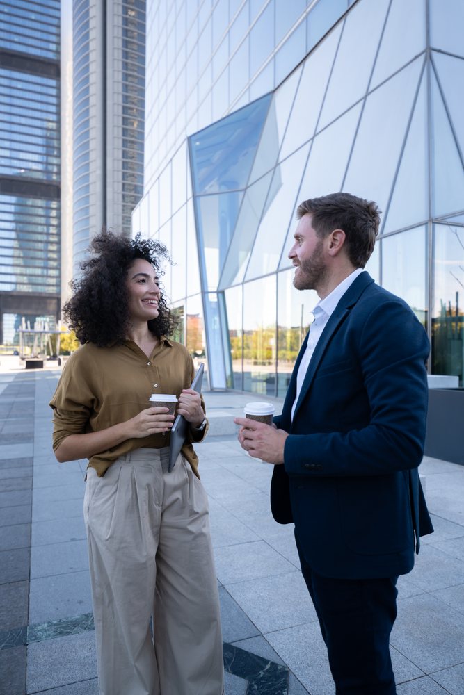 Business white professionals chatting with coffee outside modern