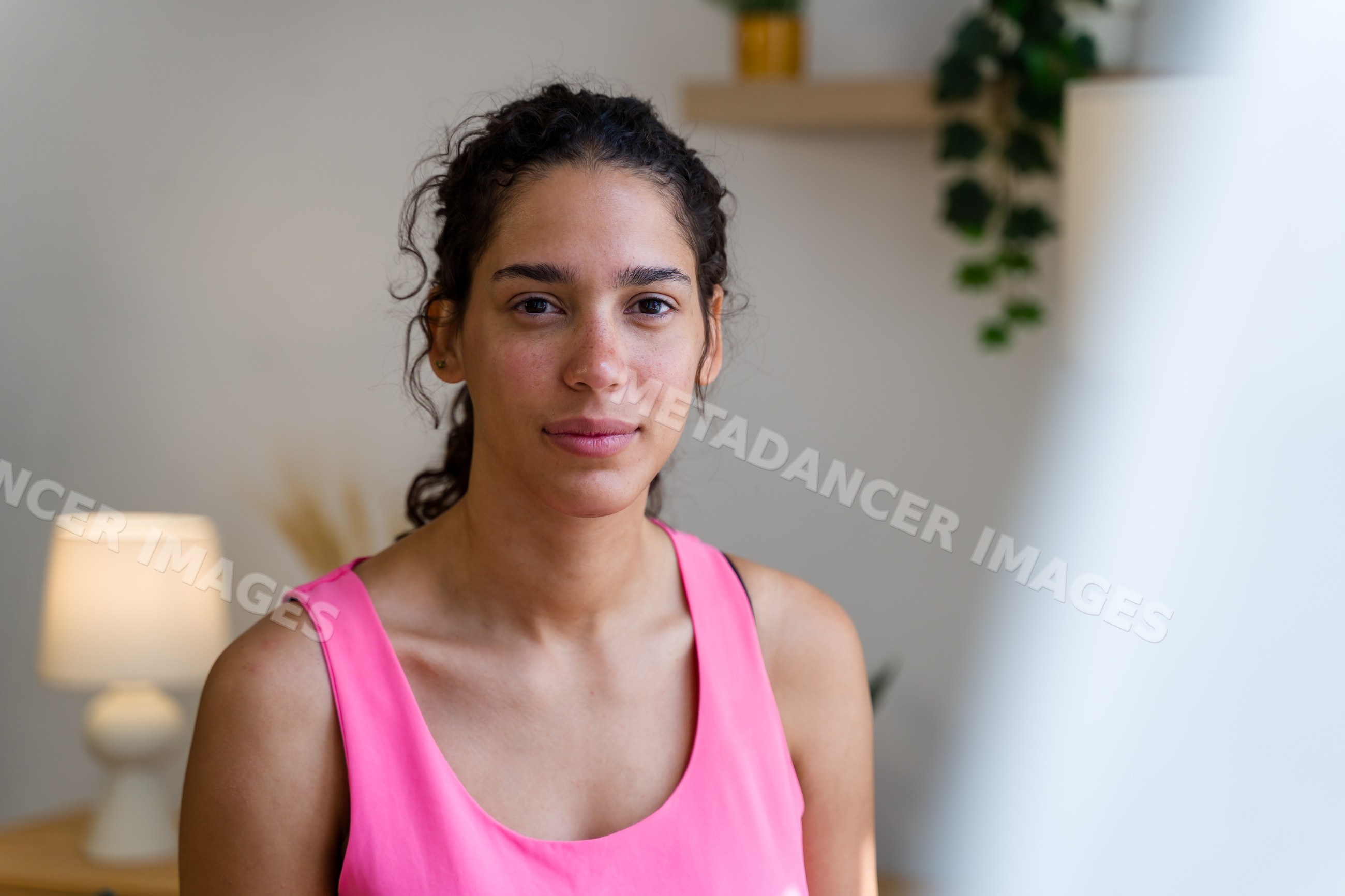 Young Hispanic woman wearing pink top posing indoors