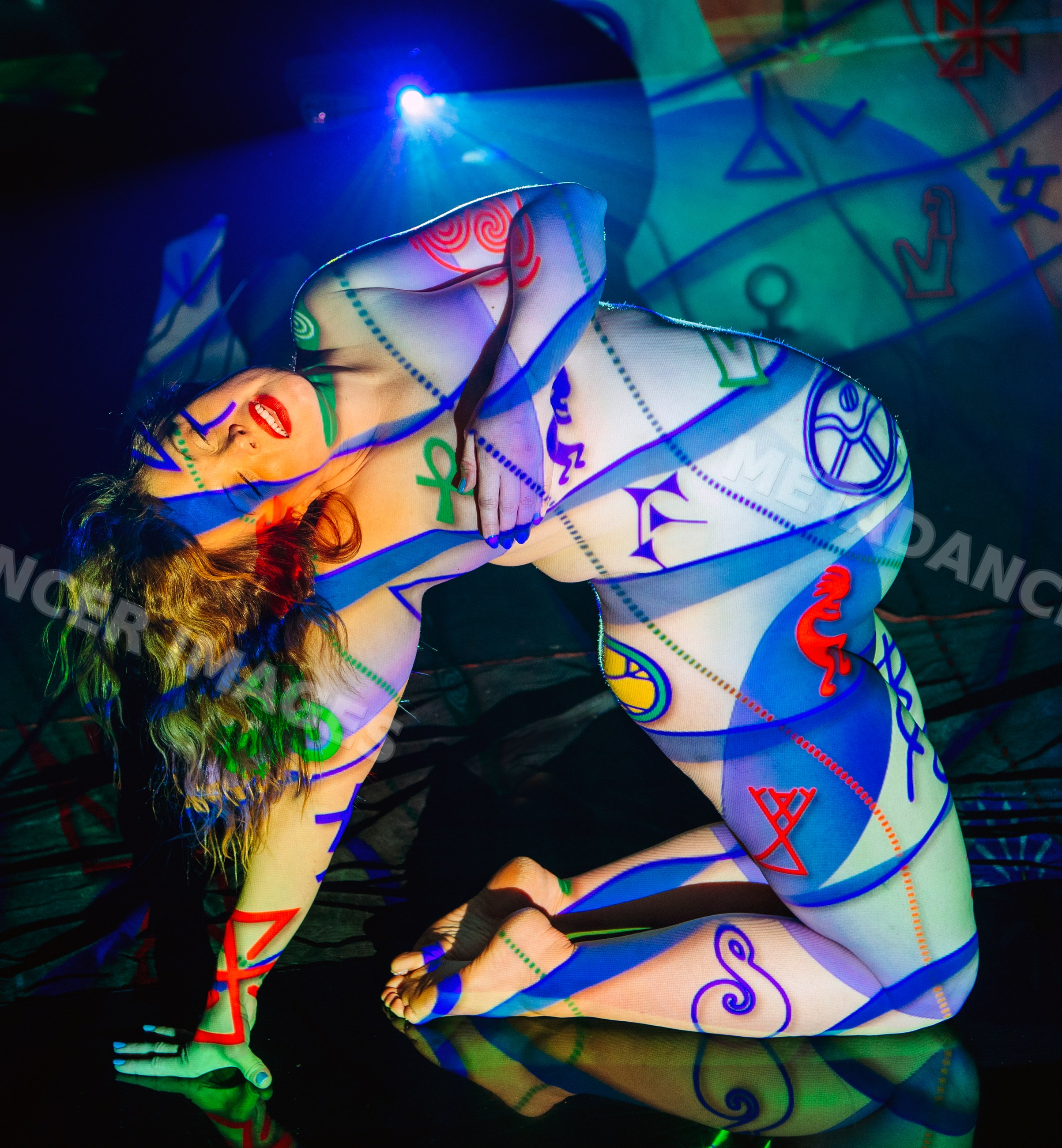 Nude white woman with colorful symbolic body painting kneeling