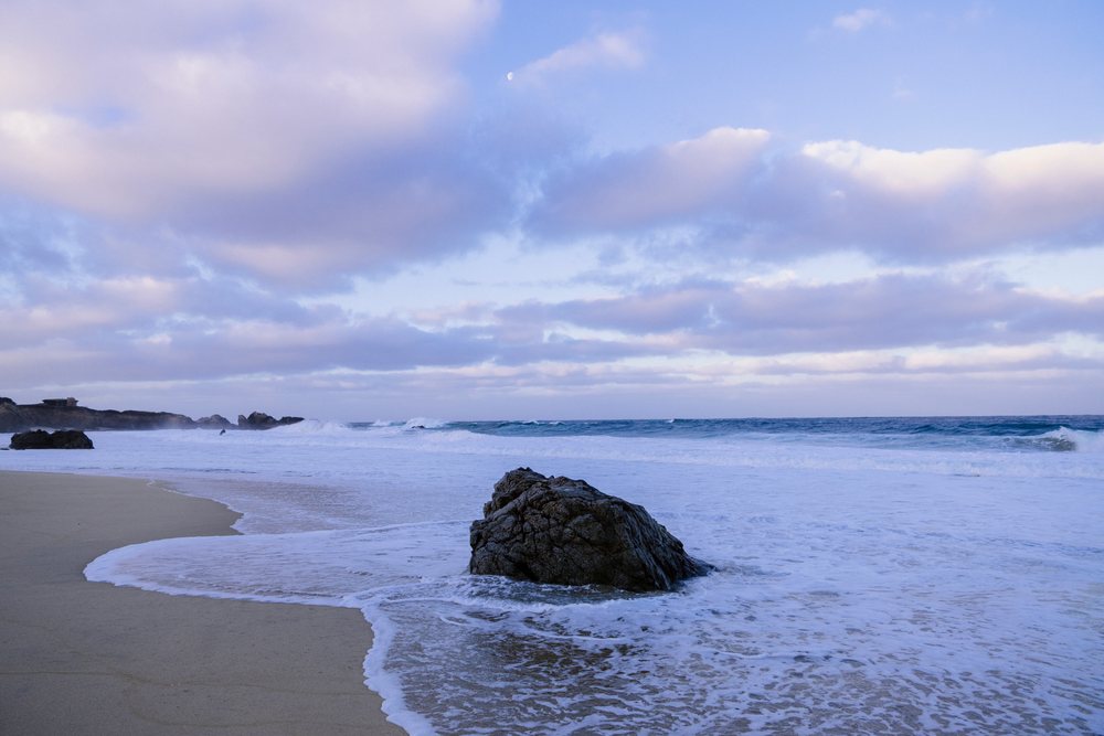 Rock at the shore with waves and clouds