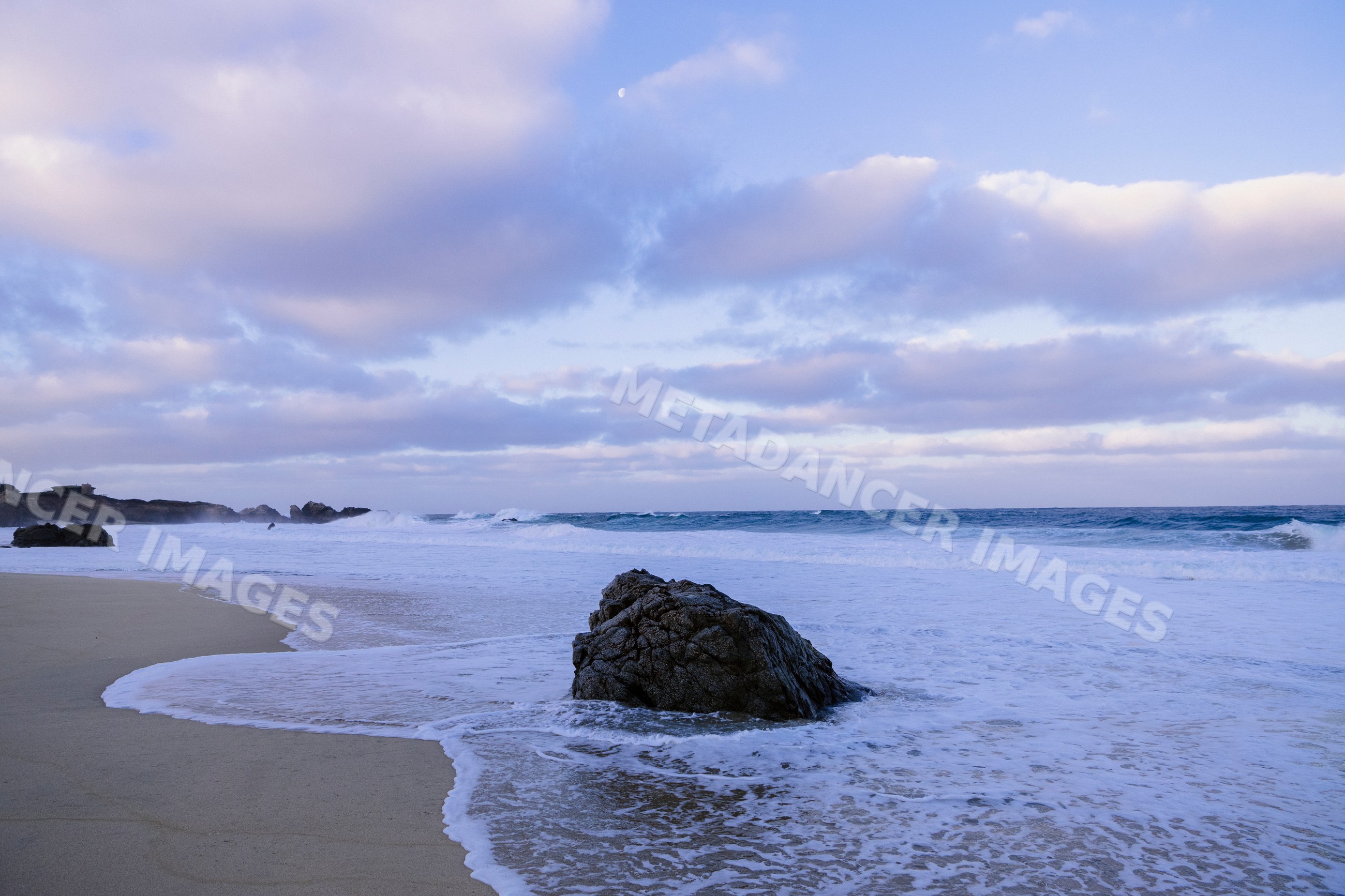 Rock at the shore with waves and clouds
