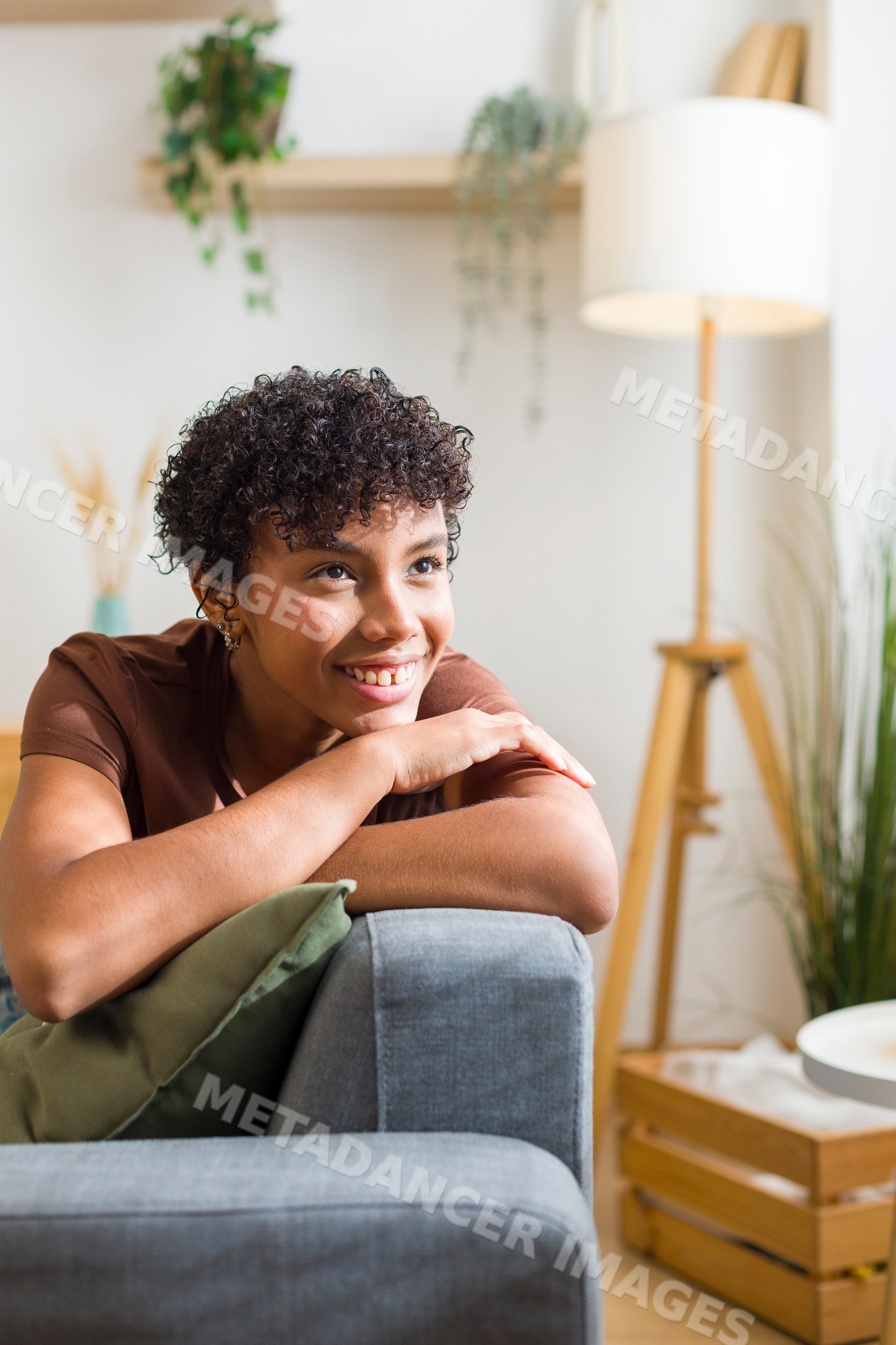 Young African American woman smiling and leaning on couch armrest