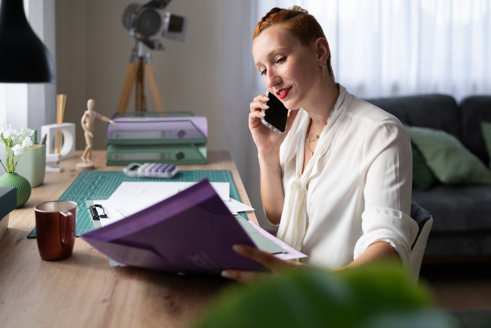 A white woman working from home talks on phone