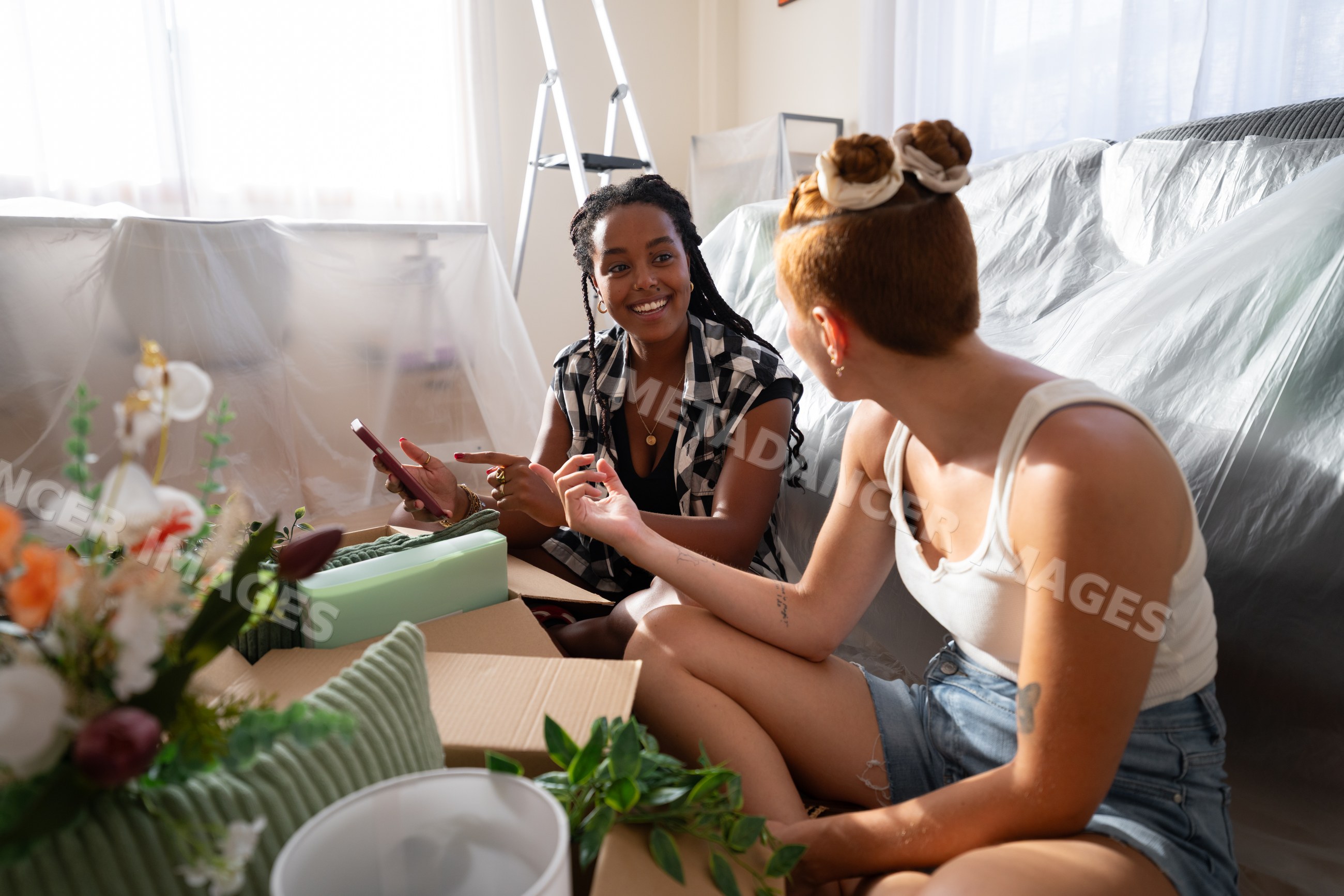 Two African American and white women pack boxes and chat during moving