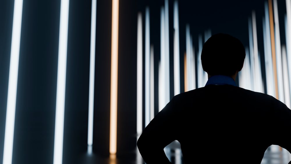 Silhouette of man standing amid vertical light pillars in dark room