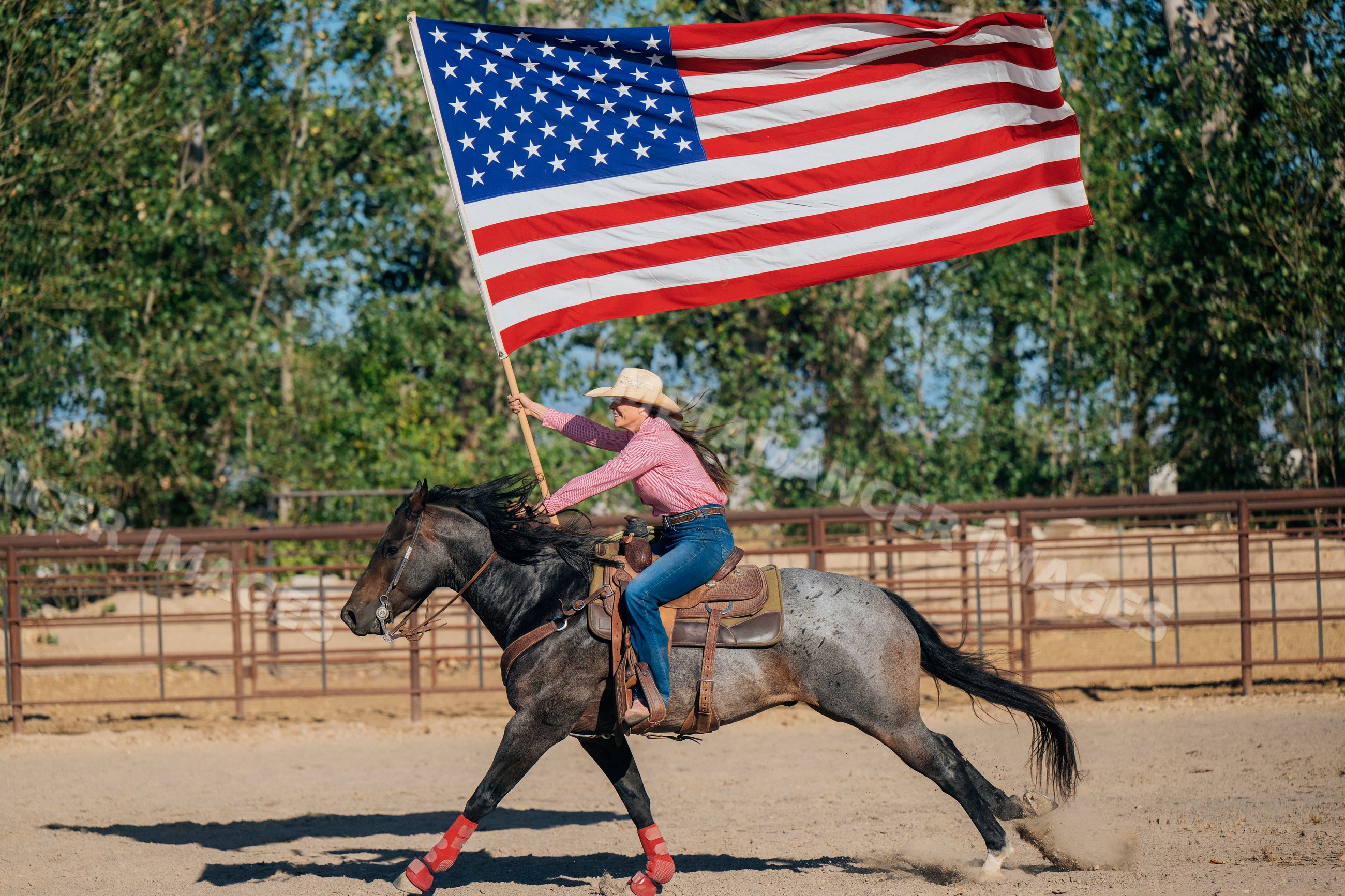 Cowgirl galloping on horseback waving american flag