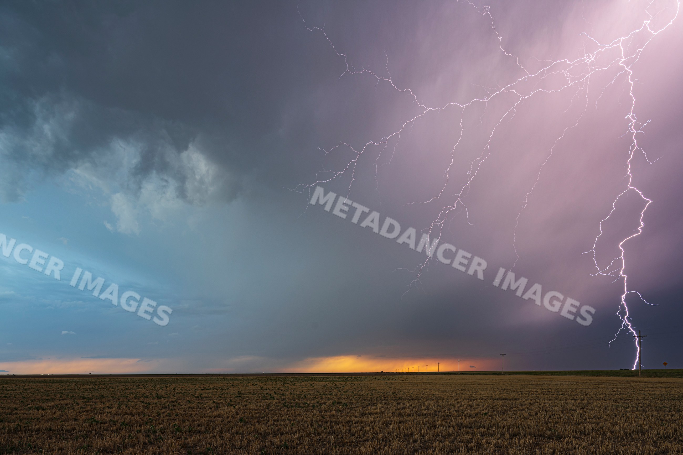 Lightning striking Storm-covered field at sunset in ulysses, kansas