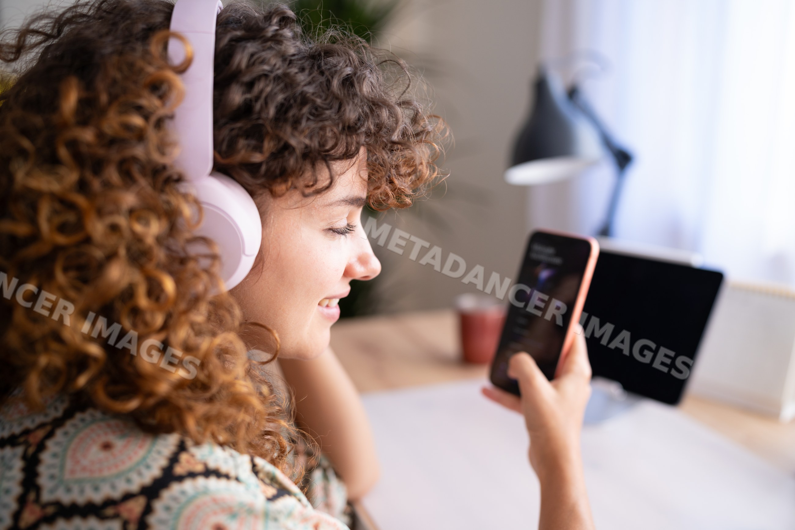 White girl with headphones using smartphone in home office in Spain