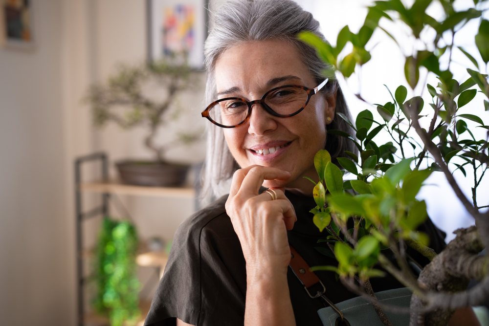 White woman holding bonsai tree indoors