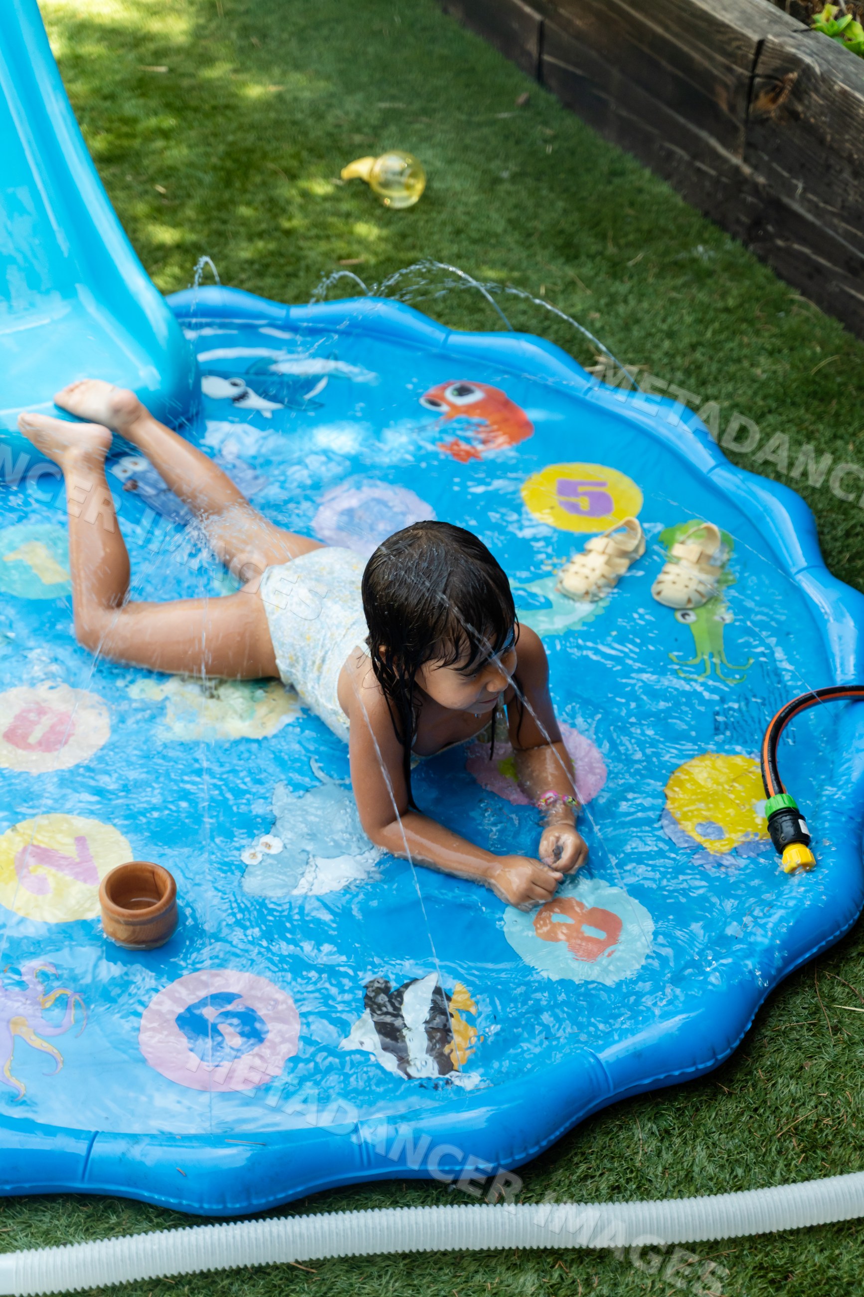 White Child playing on inflatable splash pad with water sprays