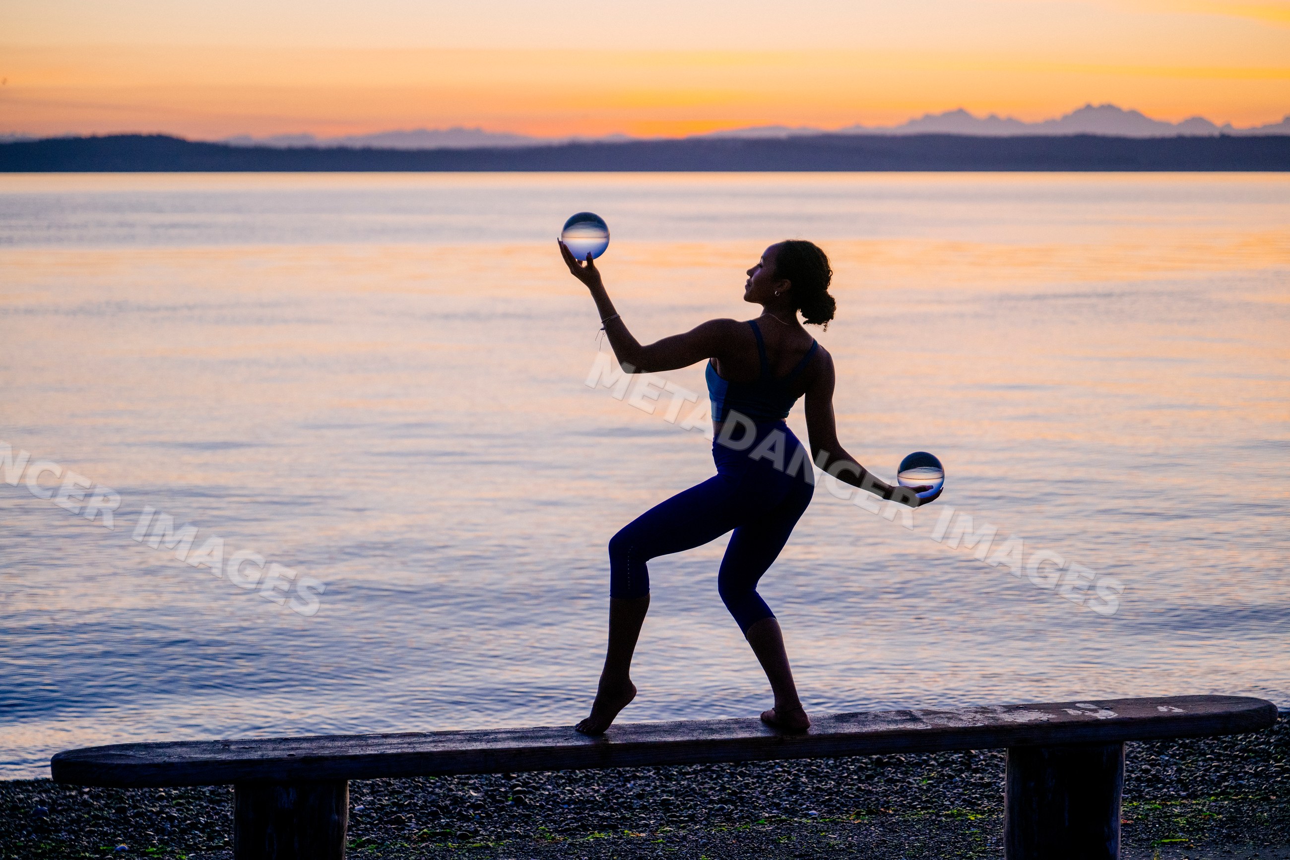 Hispanic woman balancing on bench holding crystal balls