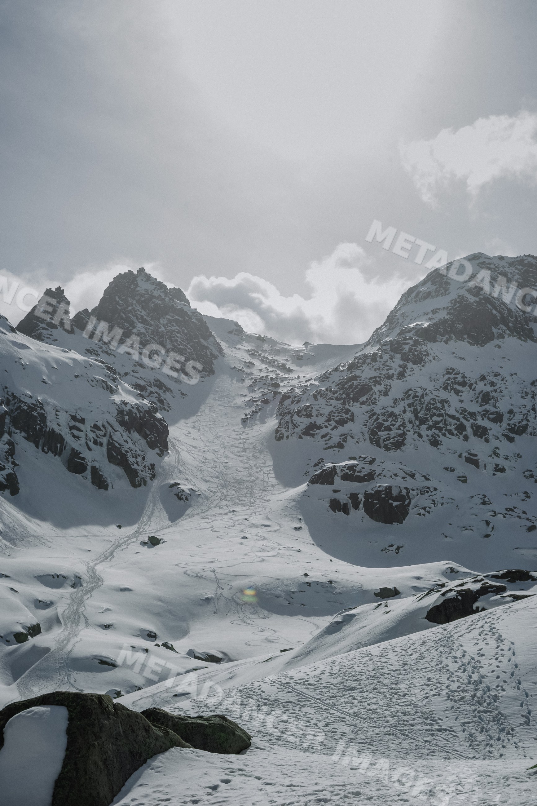 Snowy rocky mountain peak with ski tracks and footprints