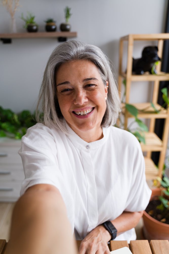 White Woman smiling taking a selfie at home with plants around