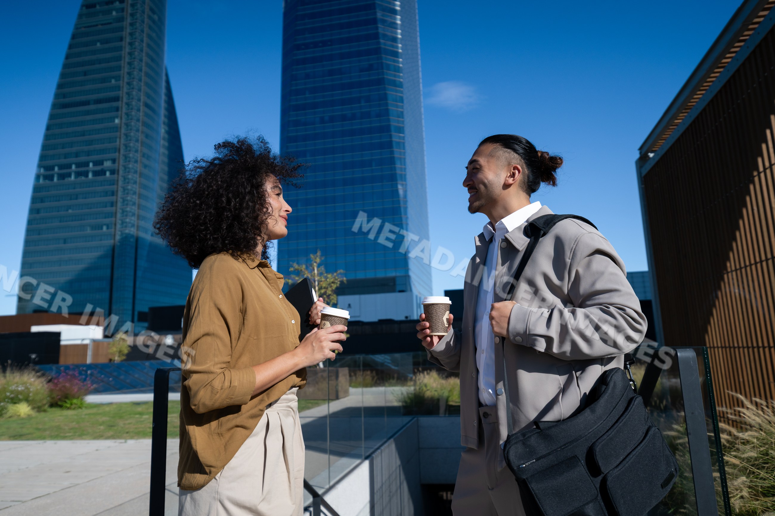 Two people holding coffee having conversation