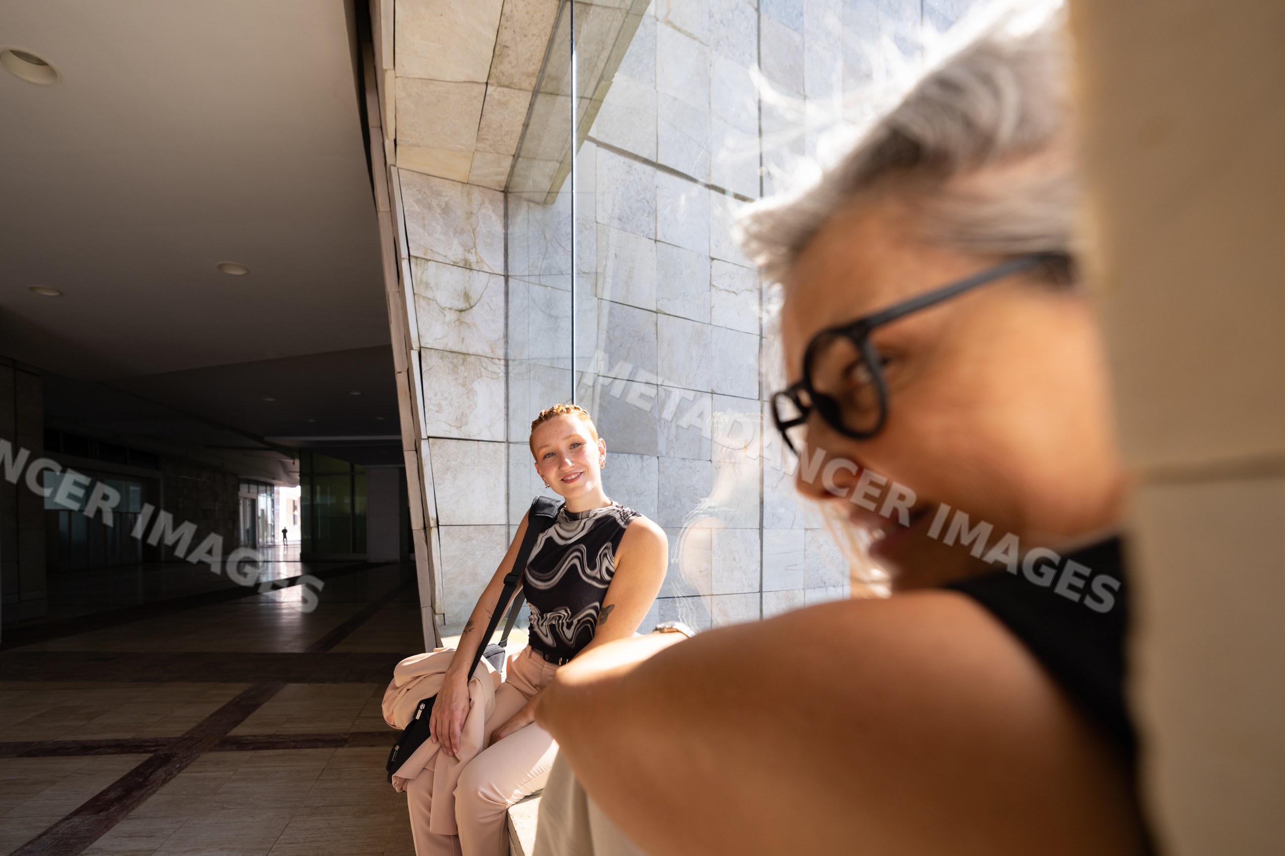 Businesswomen conversing by window in modern urban space