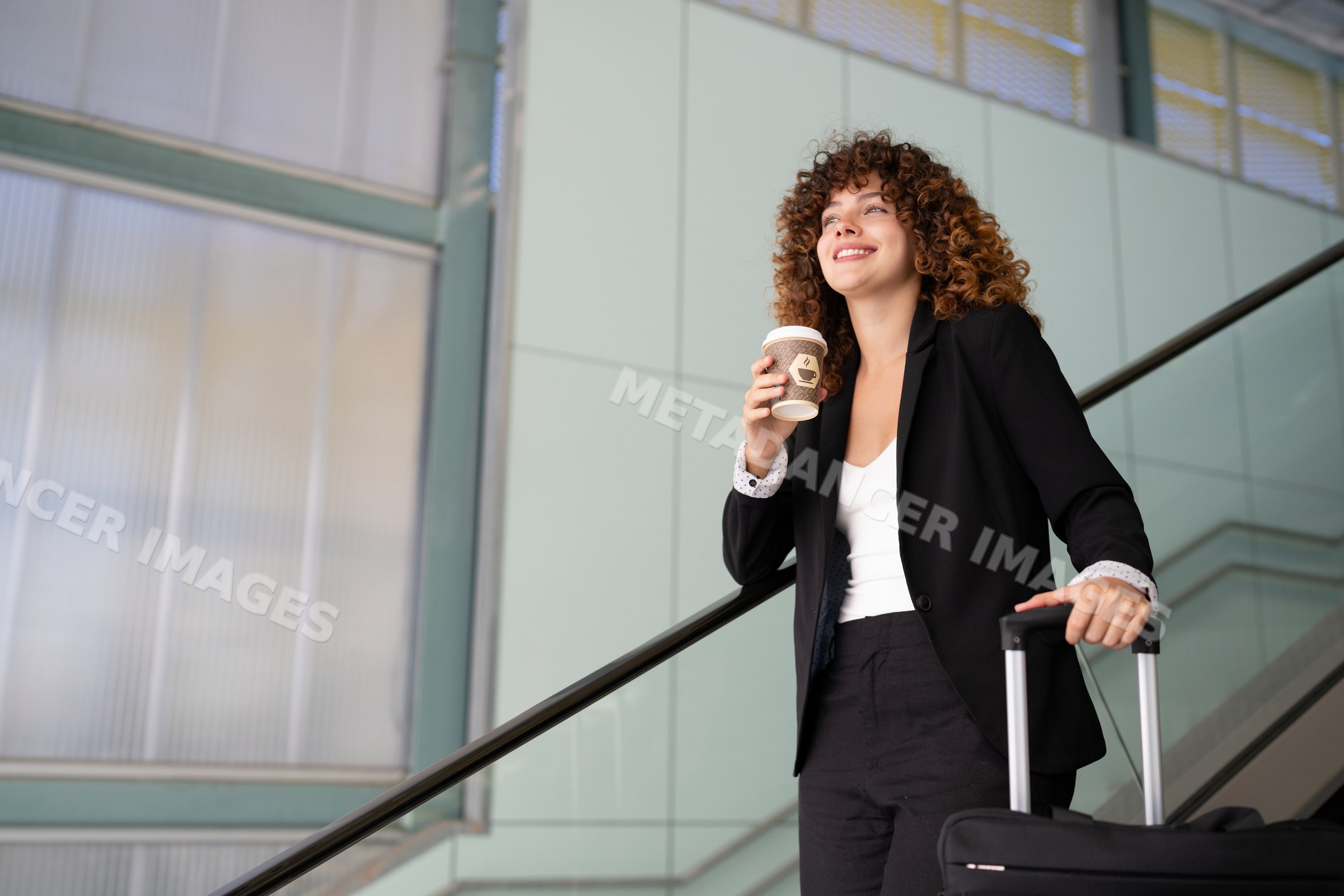 White woman holding coffee cup and suitcase