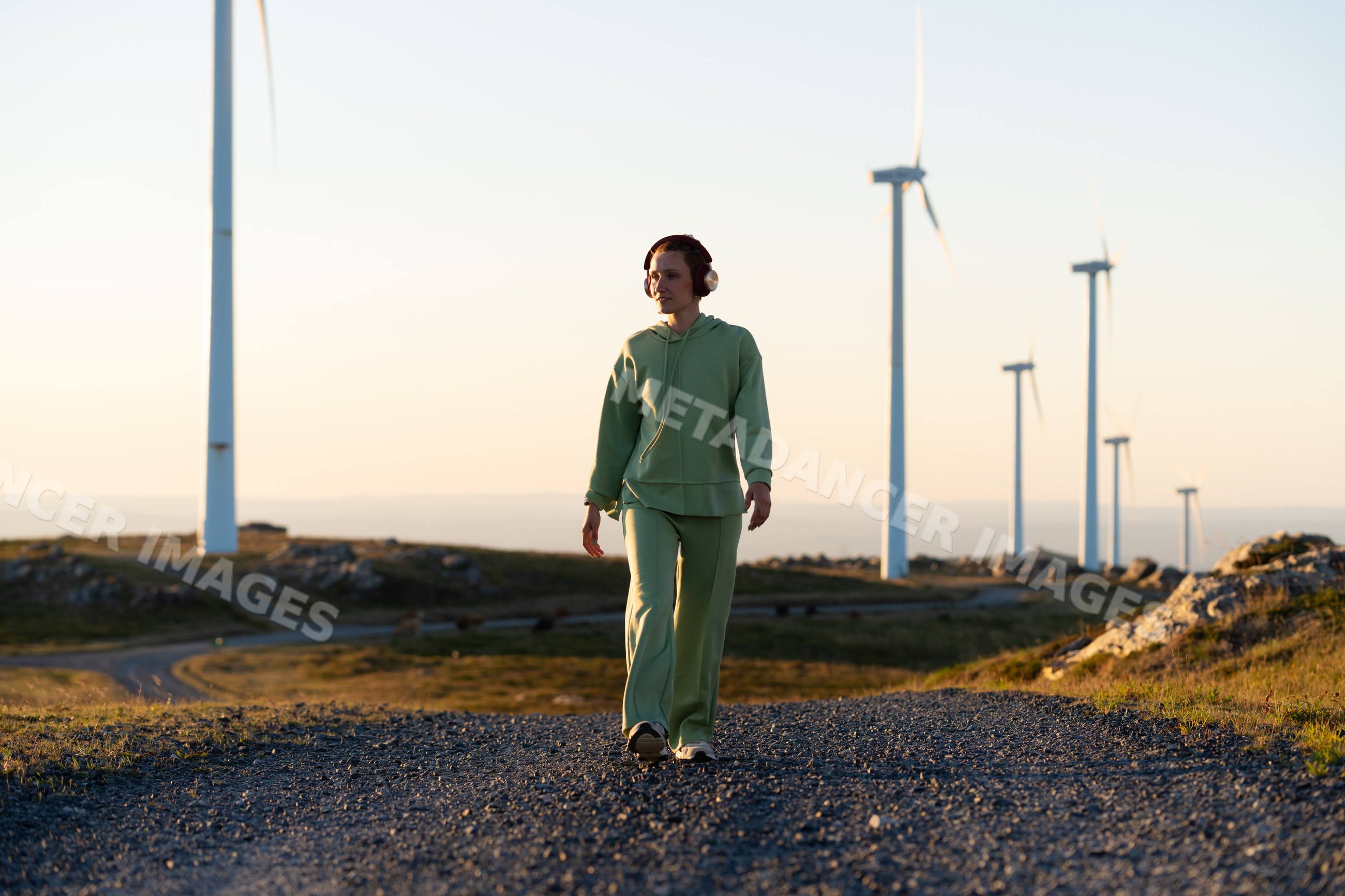 A white woman walking near wind turbines at sunset in Galicia Spain