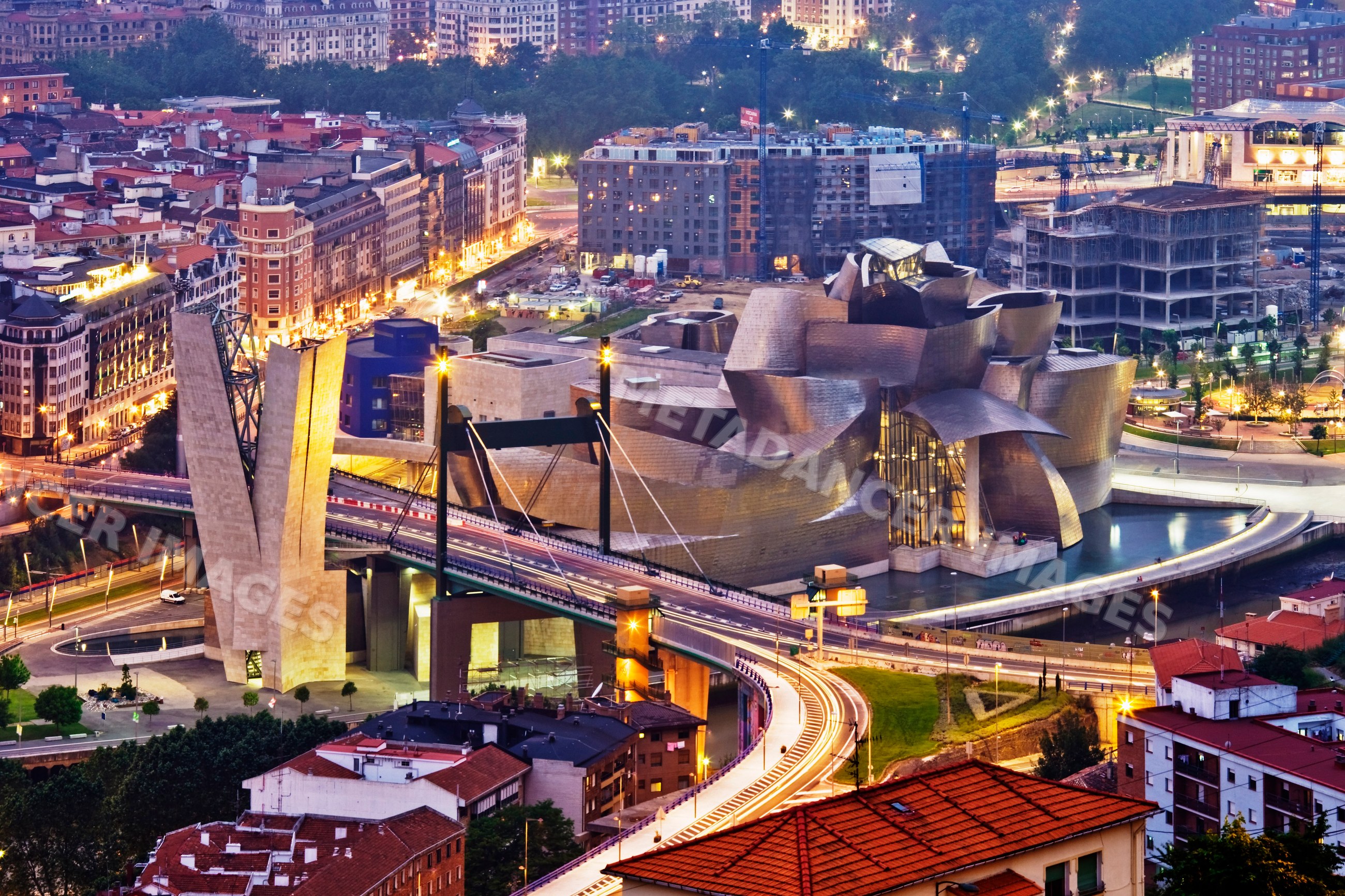 Guggenheim museum bilbao illuminated at night with urban cityscape