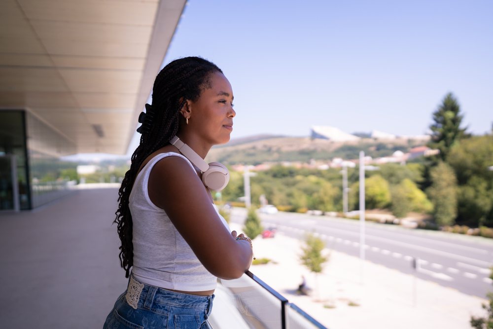 A young African American woman enjoys the view from a balcony