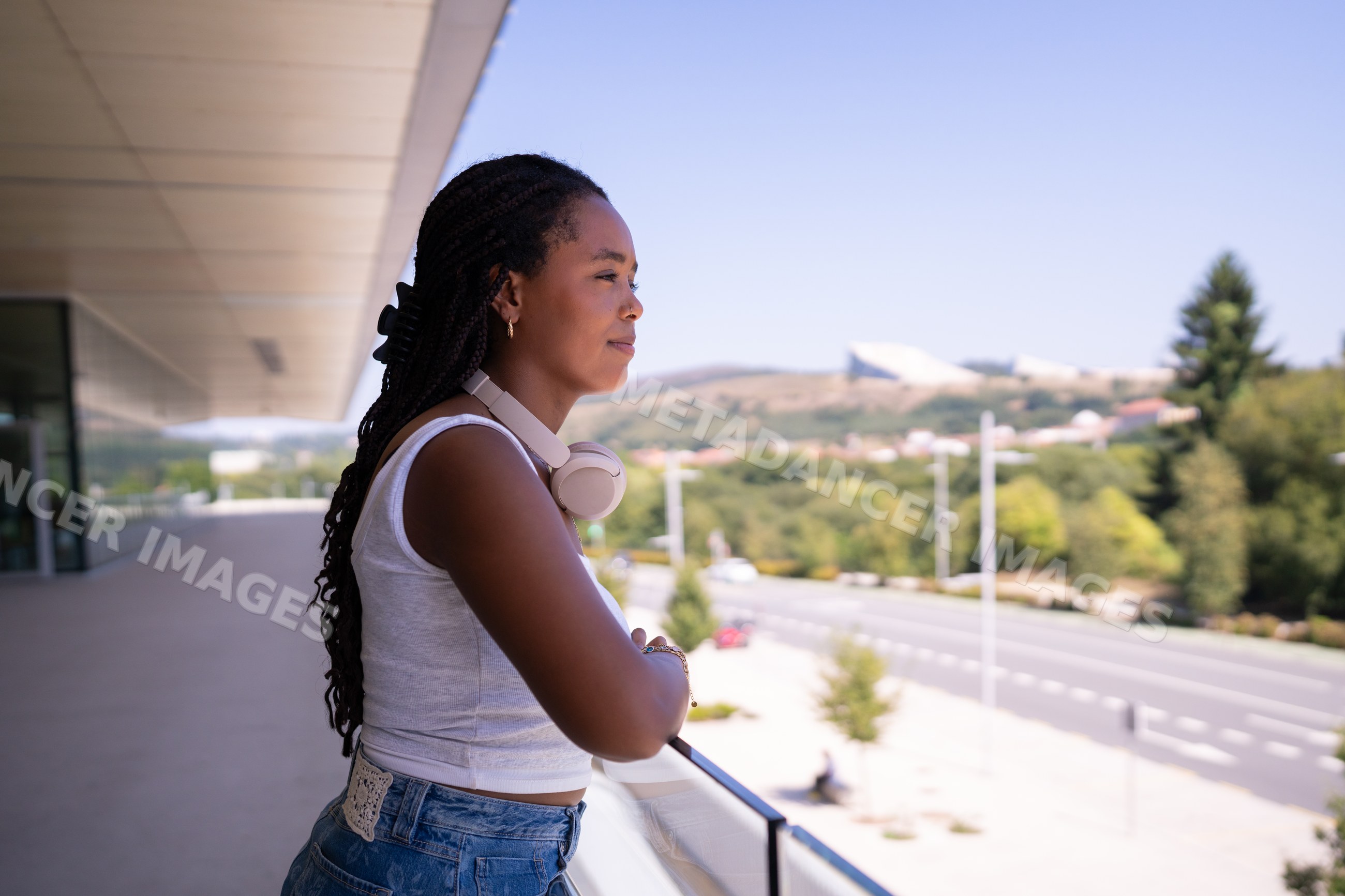 A young African American woman enjoys the view from a balcony