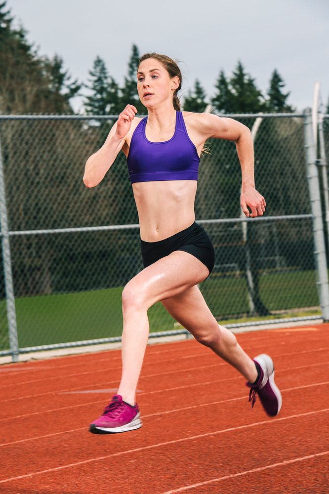 White woman running on outdoor track during athletic training