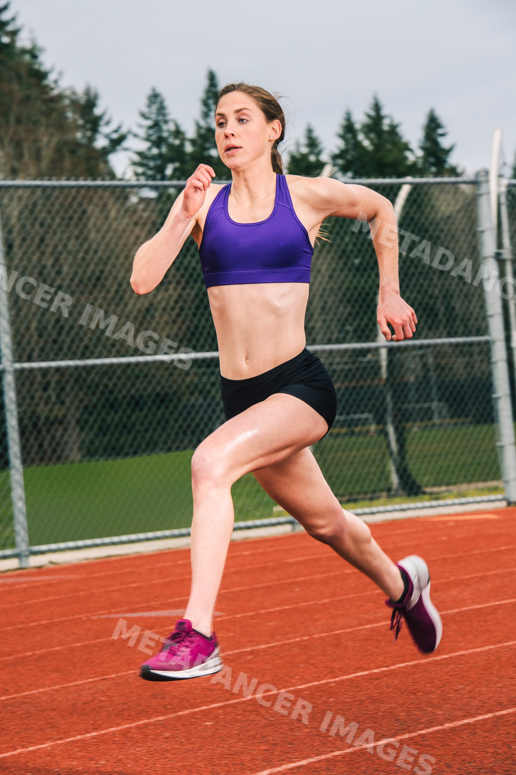 White woman running on outdoor track during athletic training