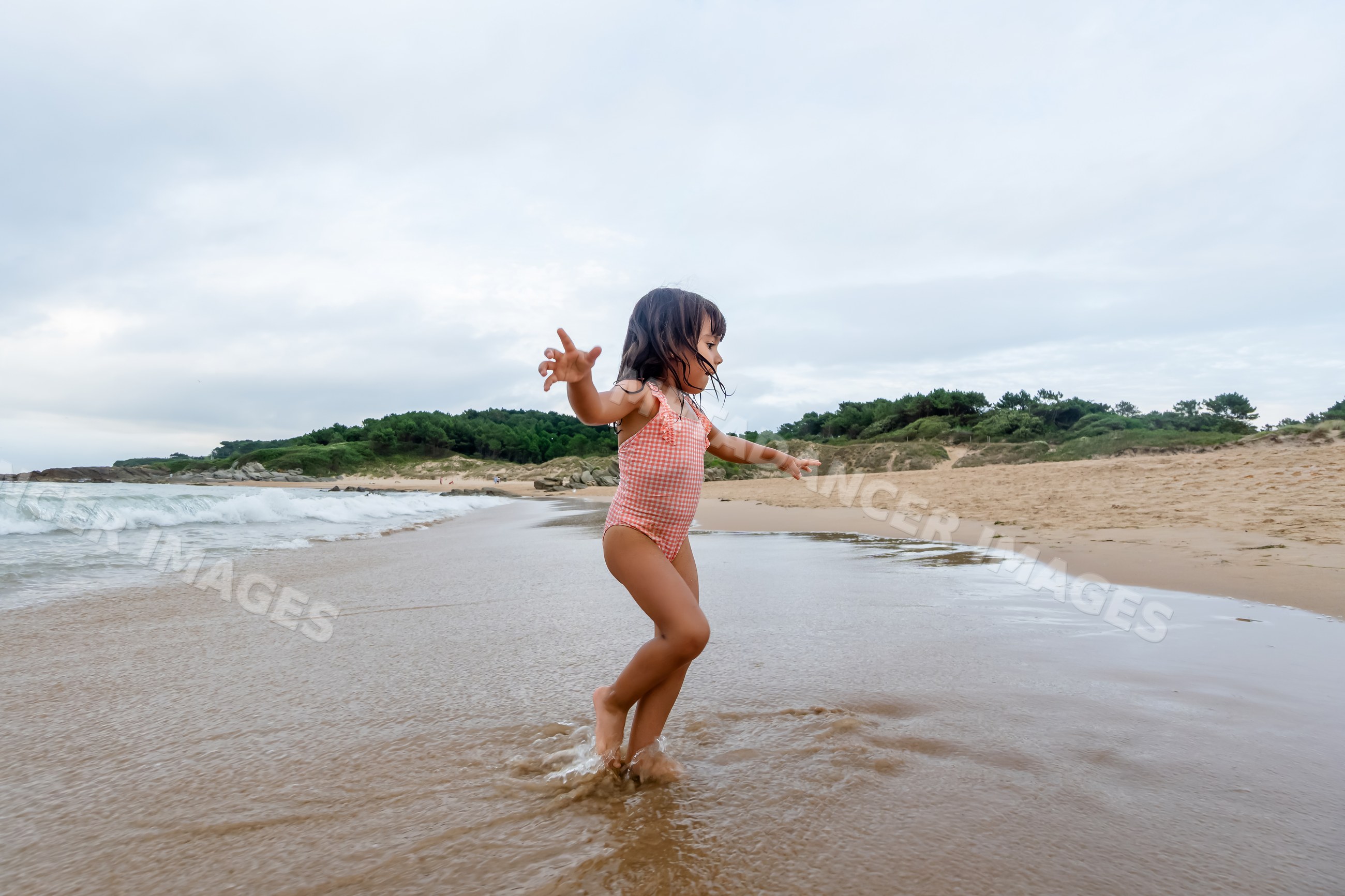 White child girl playing in water on sandy beach coast in a beach