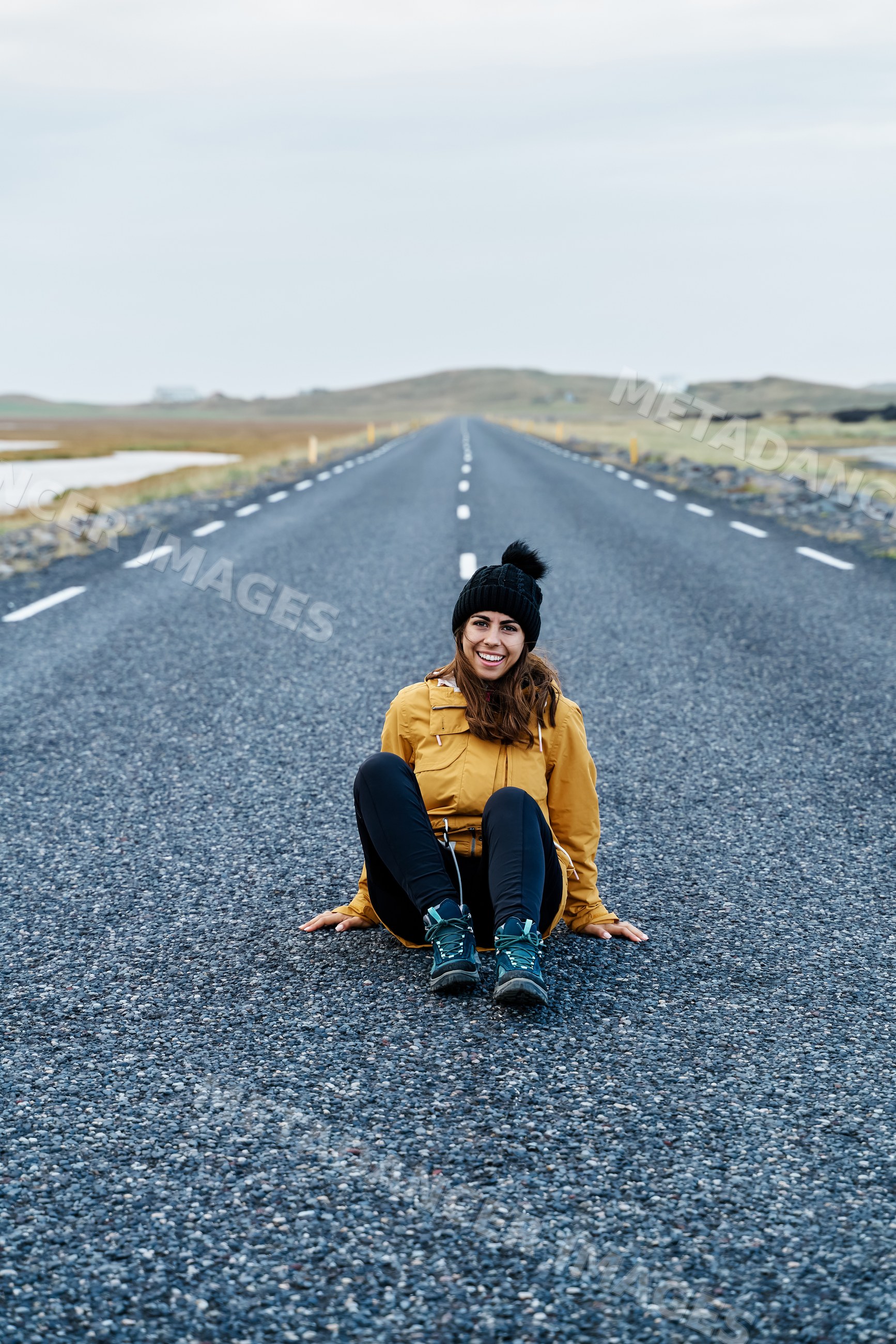 A white woman in a yellow jacket sitting on an empty road