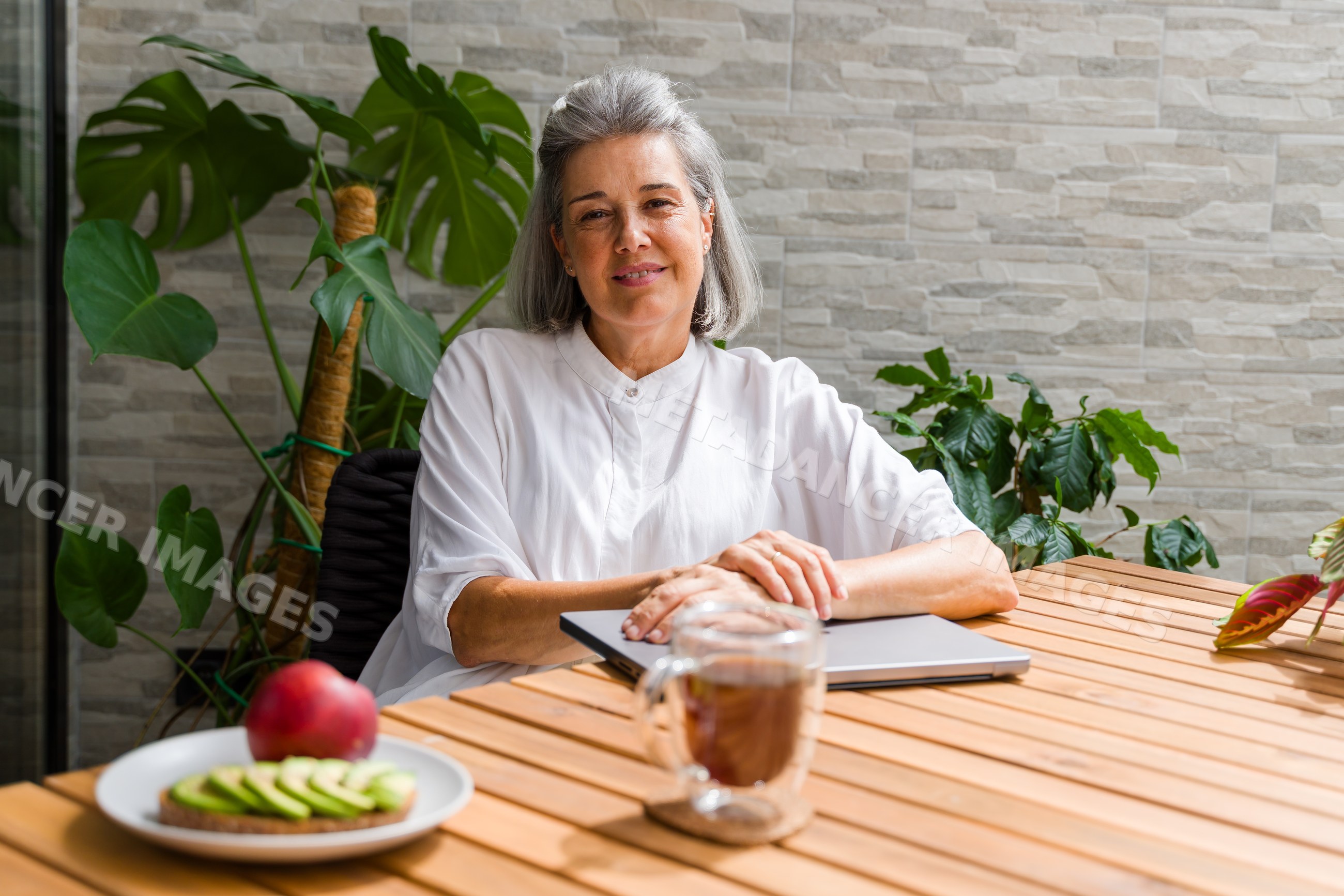 Senior white woman sitting with laptop and healthy breakfast