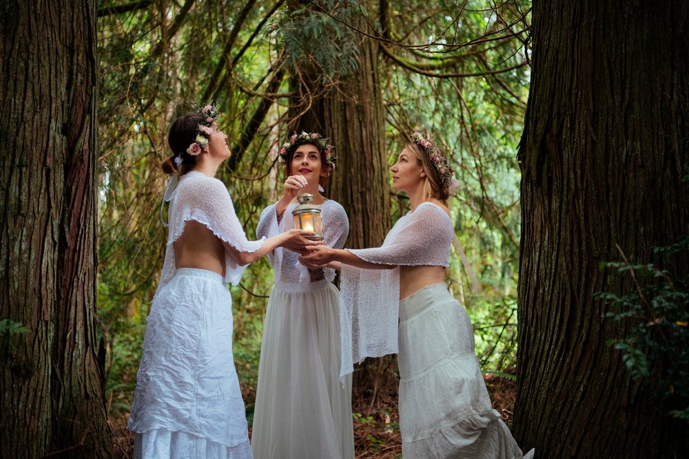 Women in white clothing holding lantern in forest