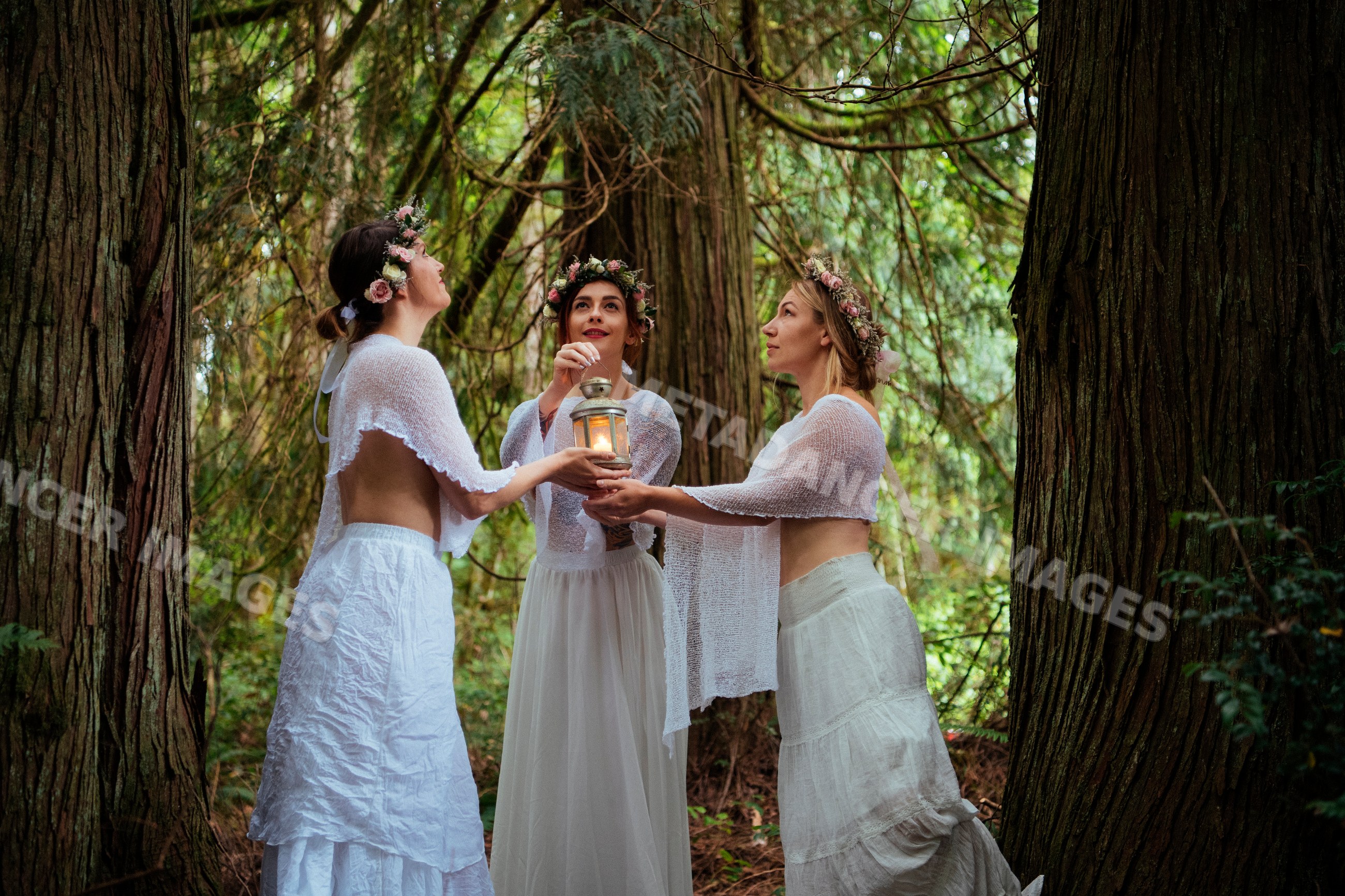 Women in white clothing holding lantern in forest