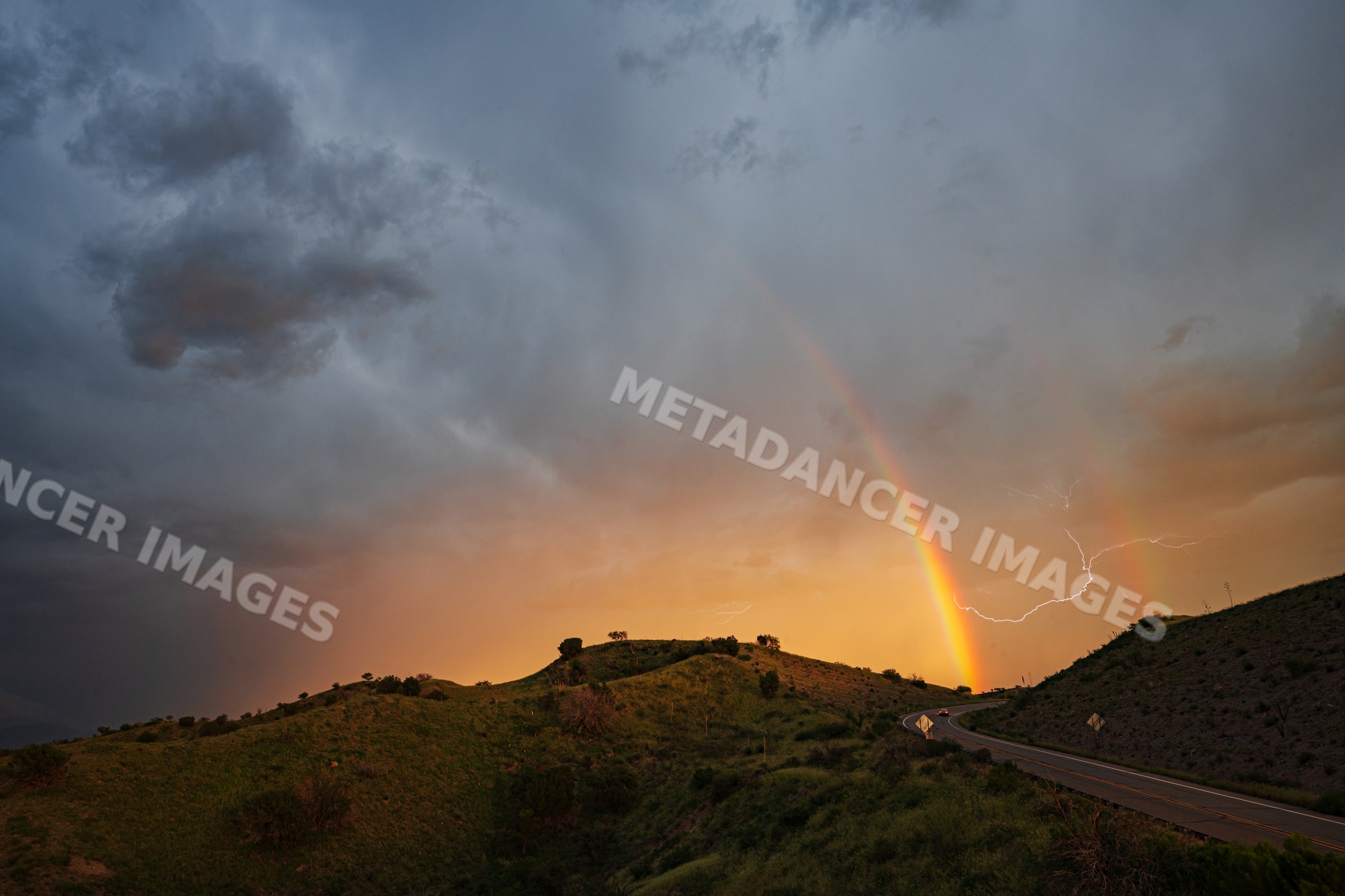 Rainbow and lightning storm over hillside on arizona highway 83