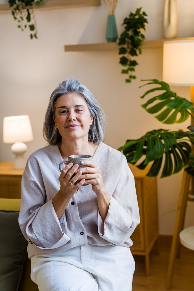White woman relaxing and drinking coffee in cozy living room