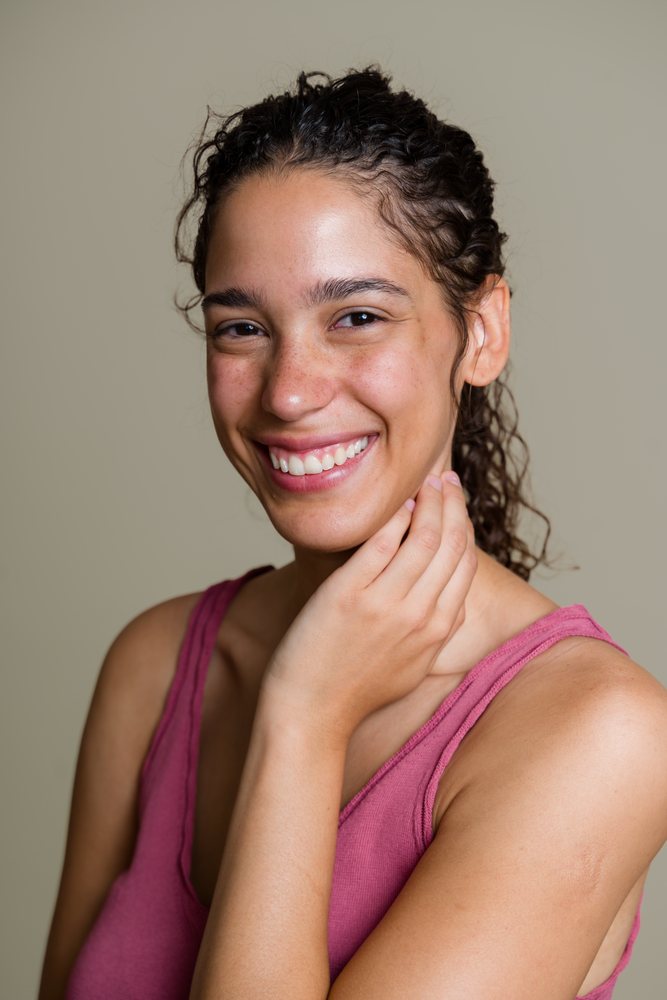 Portrait of smiling Hispanic woman touching her face
