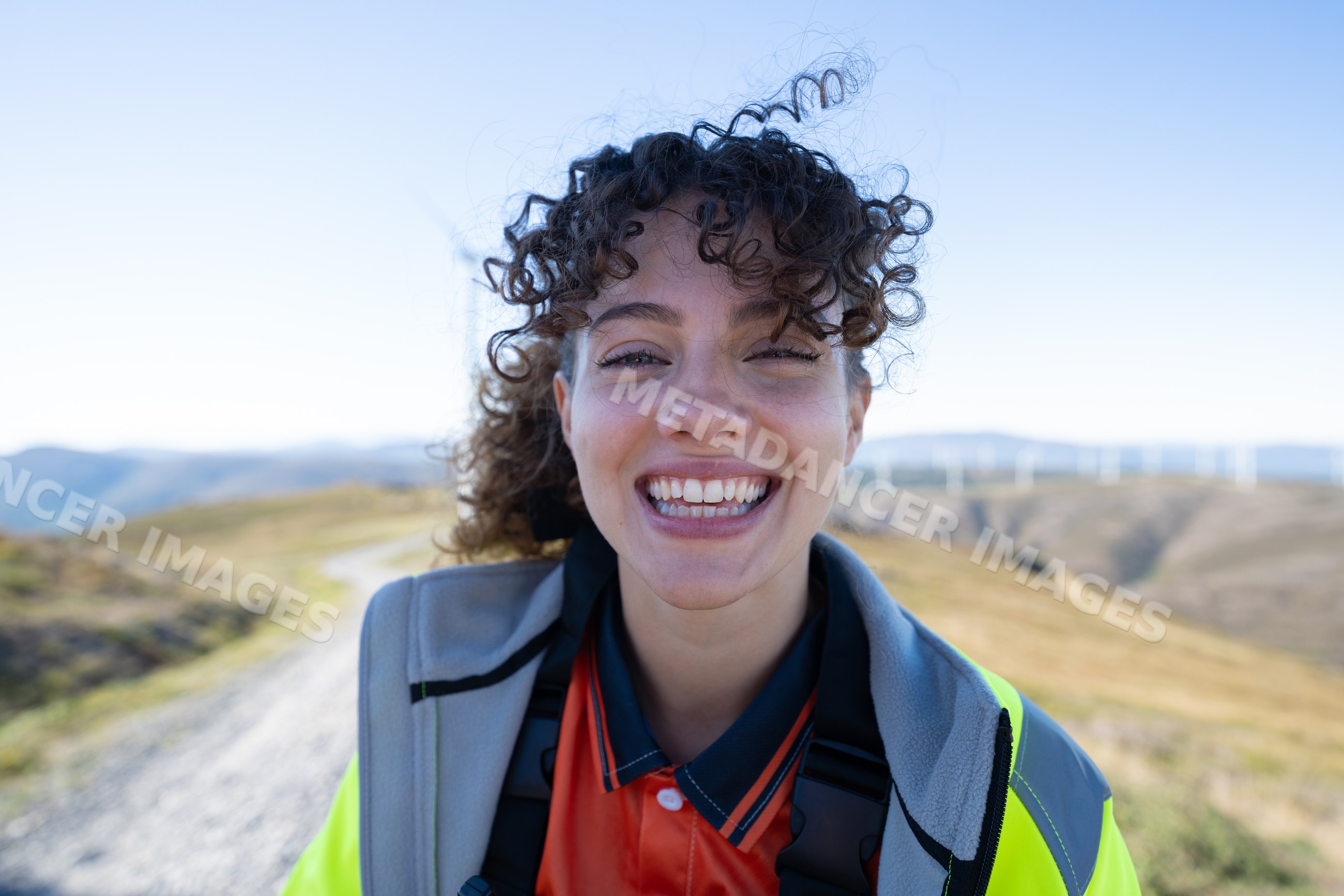 White woman smiling outdoors with wind turbines