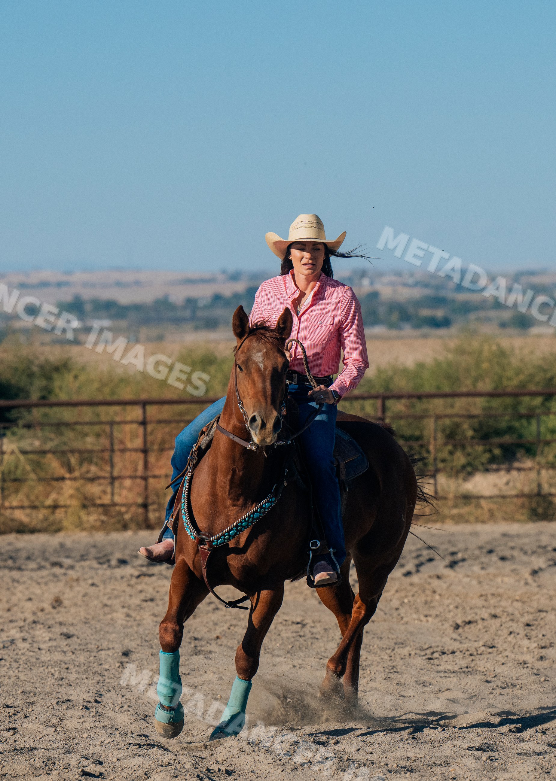 White woman riding horse in open ranch setting