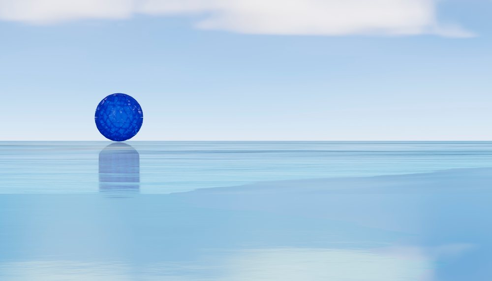 Blue geometric sphere floating above calm water reflecting sky