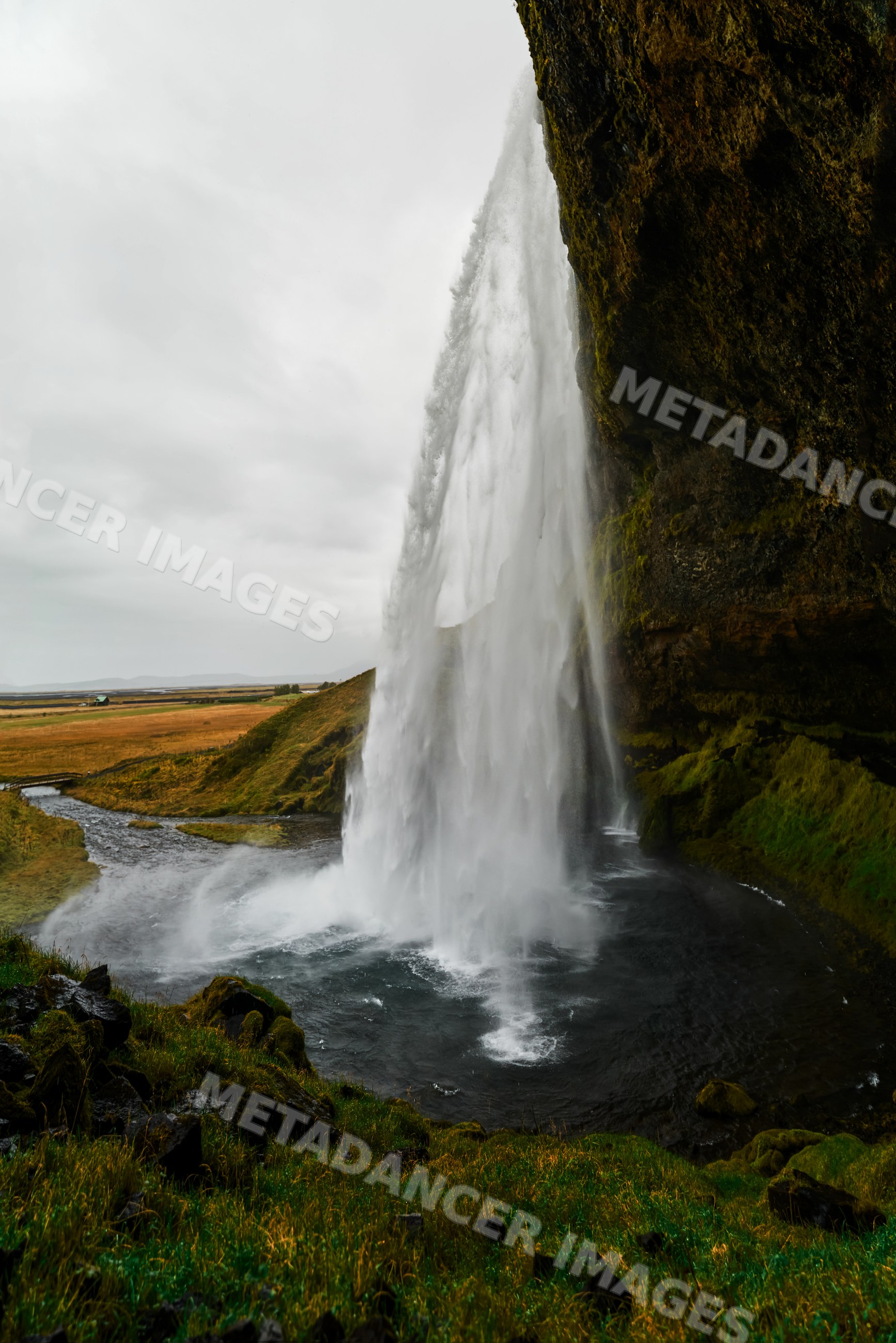 Waterfall cascading over mossy cliff into river