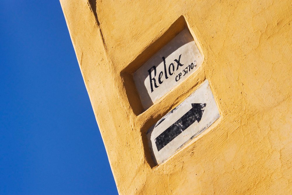 Street sign with relax and arrow on yellow wall