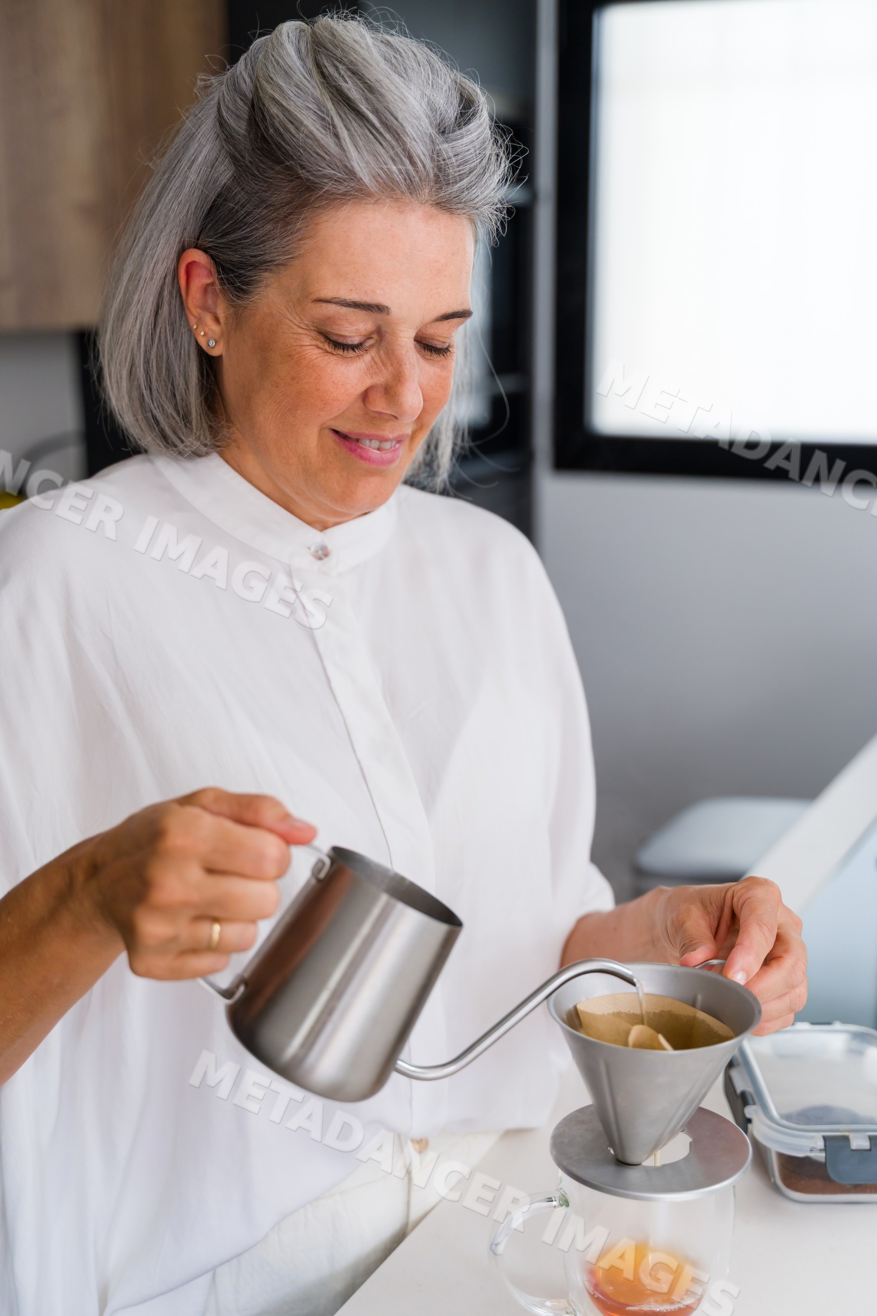 White Woman pouring hot water to brew pour over coffee in kitchen