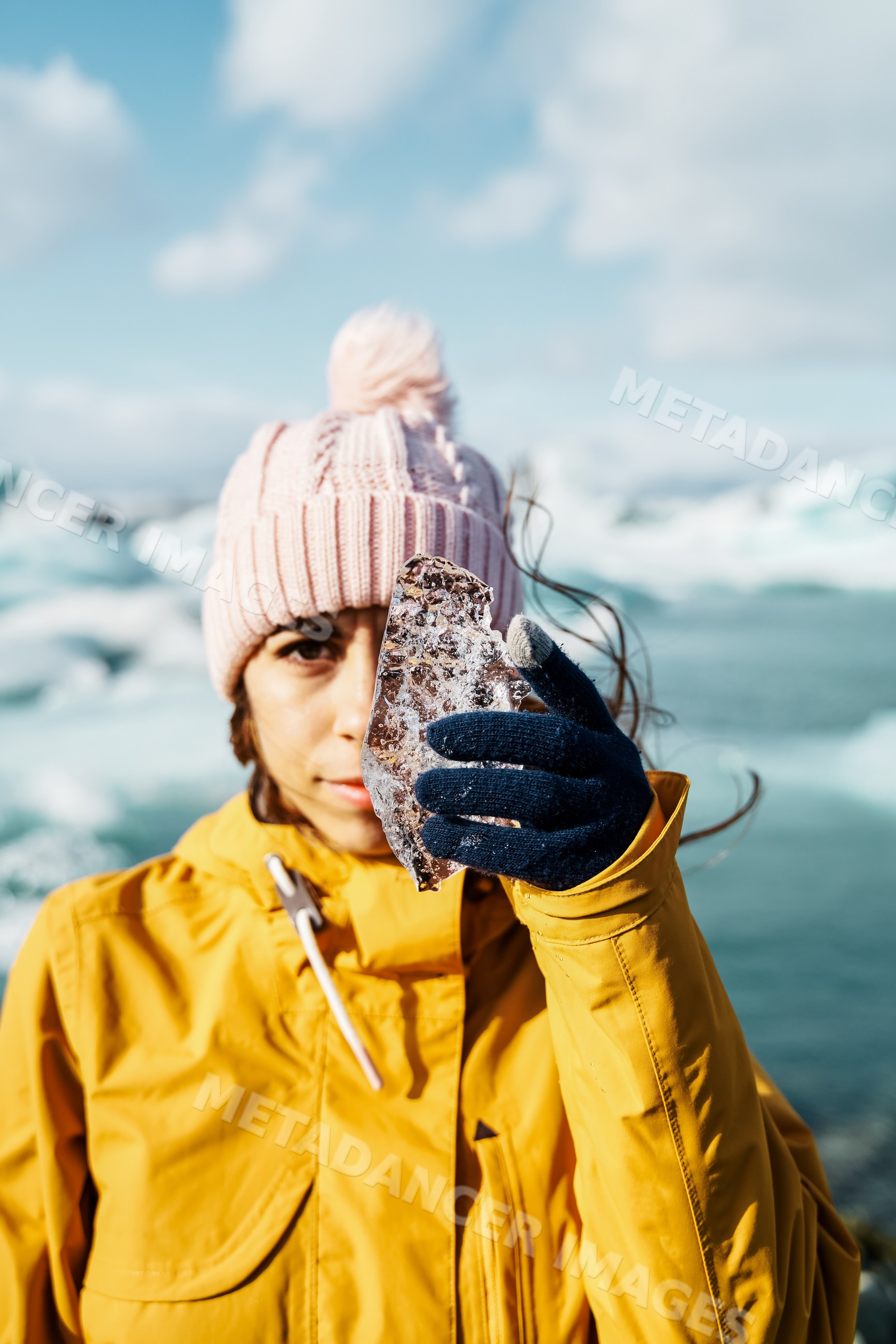 A white woman holds a piece of ice near a frozen landscape