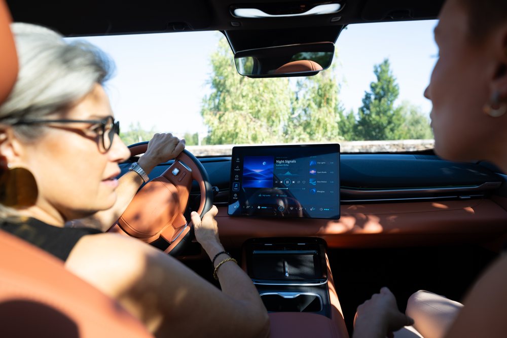 White woman driving car with touchscreen dashboard and passenger