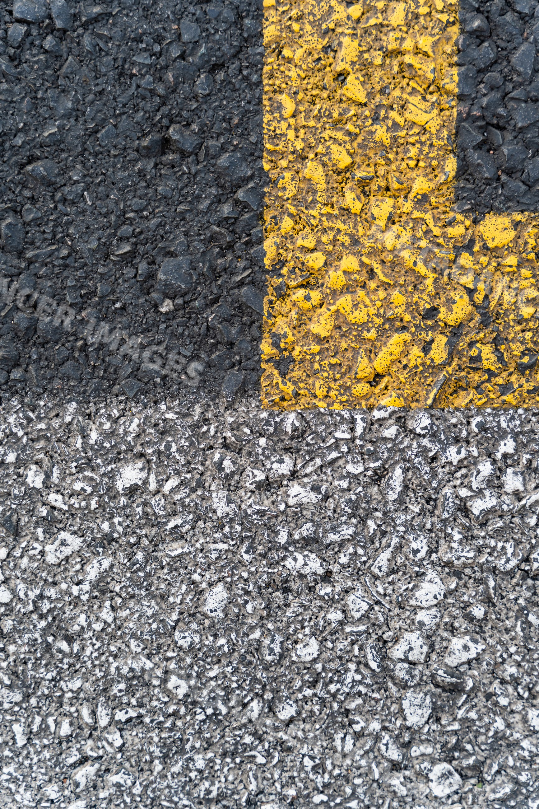 Close-up of asphalt road surface with yellow and white markings